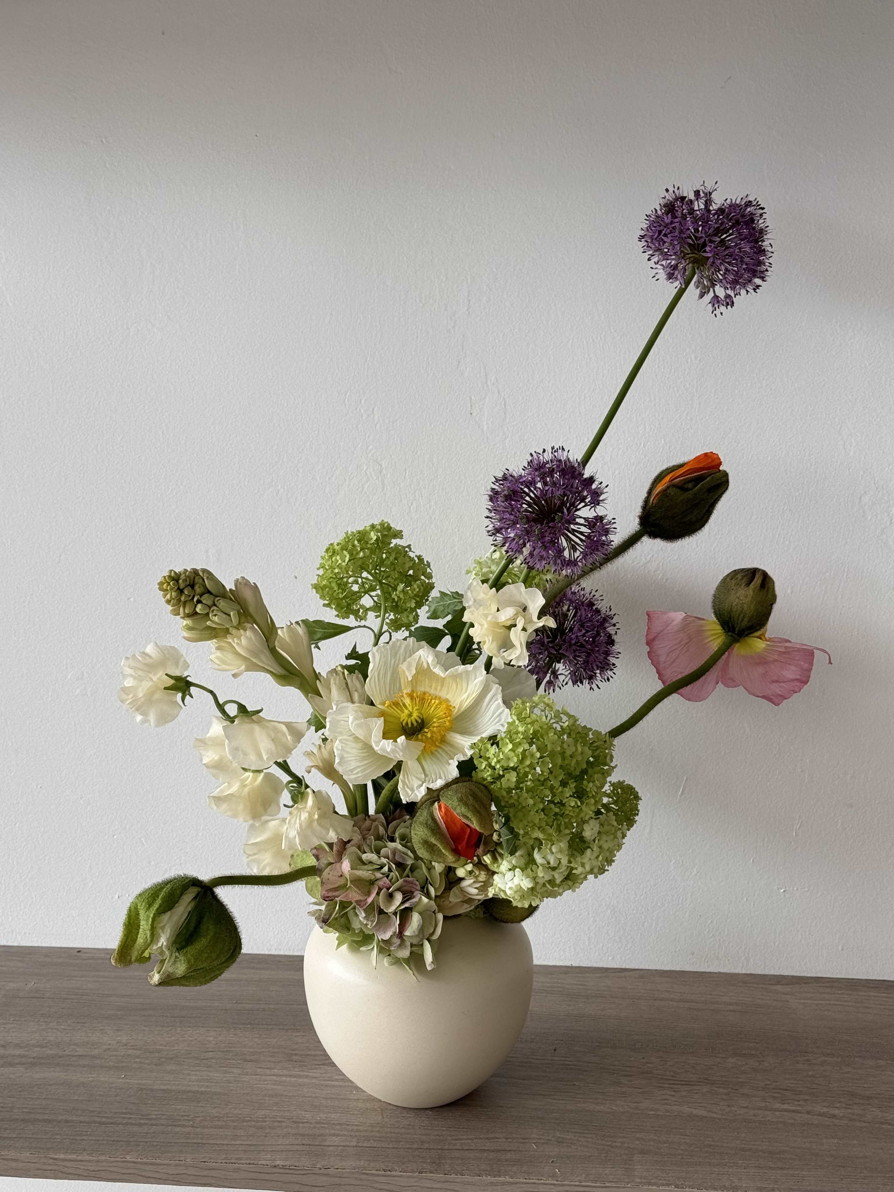 White vase arrangement with white, green, purple, and pink flowers