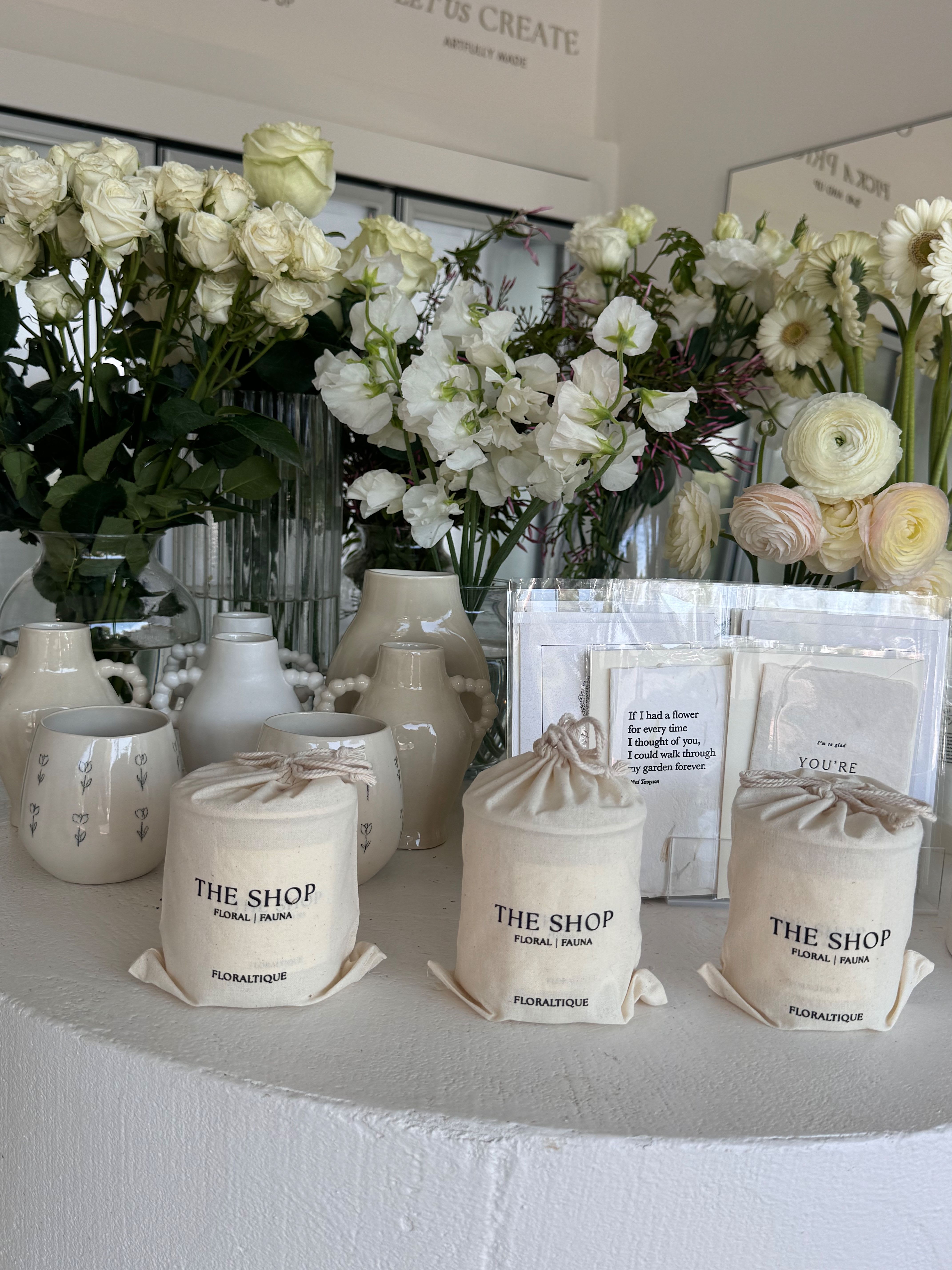 White floral arrangements with roses, ranunculus, and daisies in ceramic vases