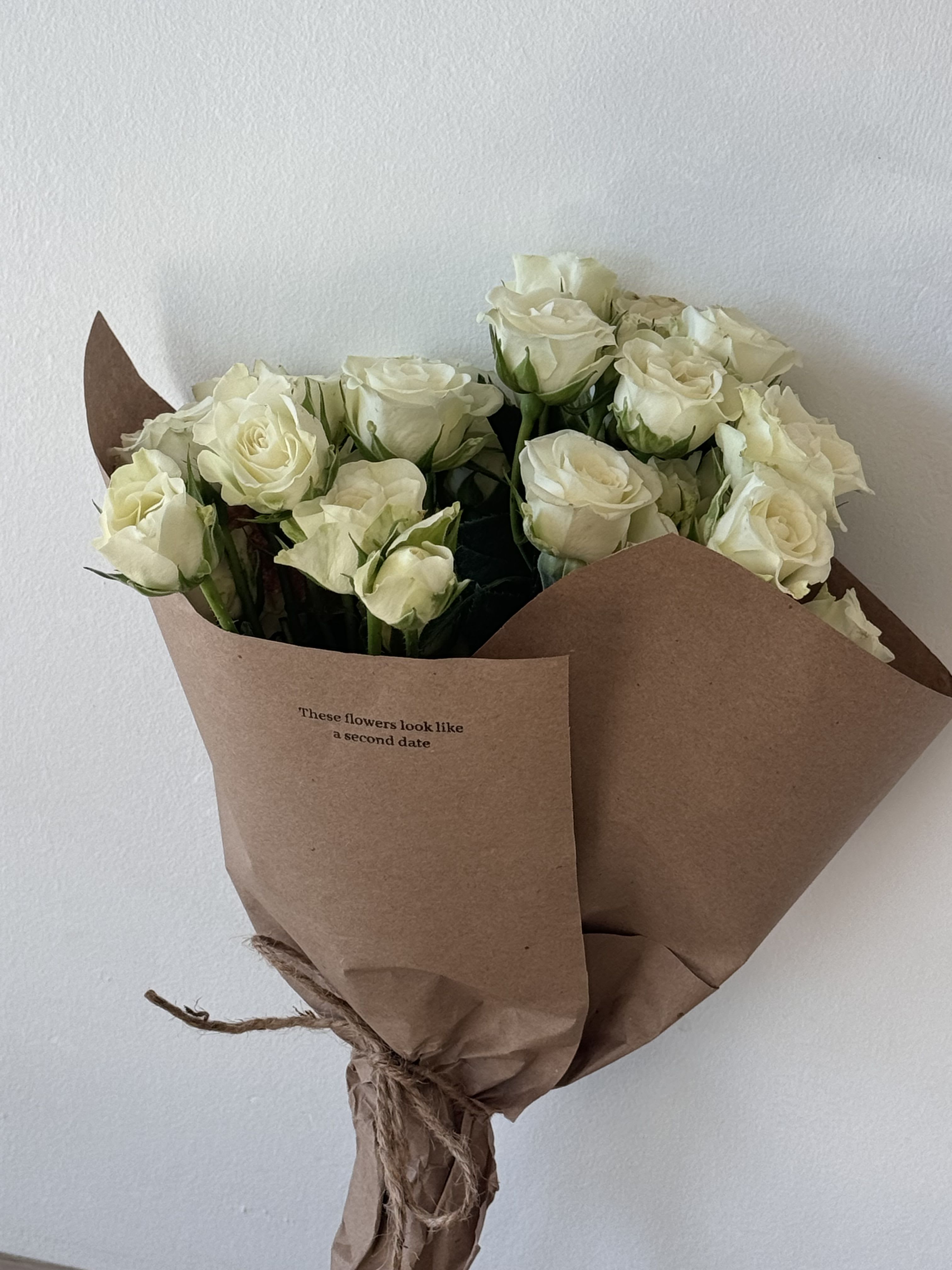Bouquet of white roses wrapped in brown paper