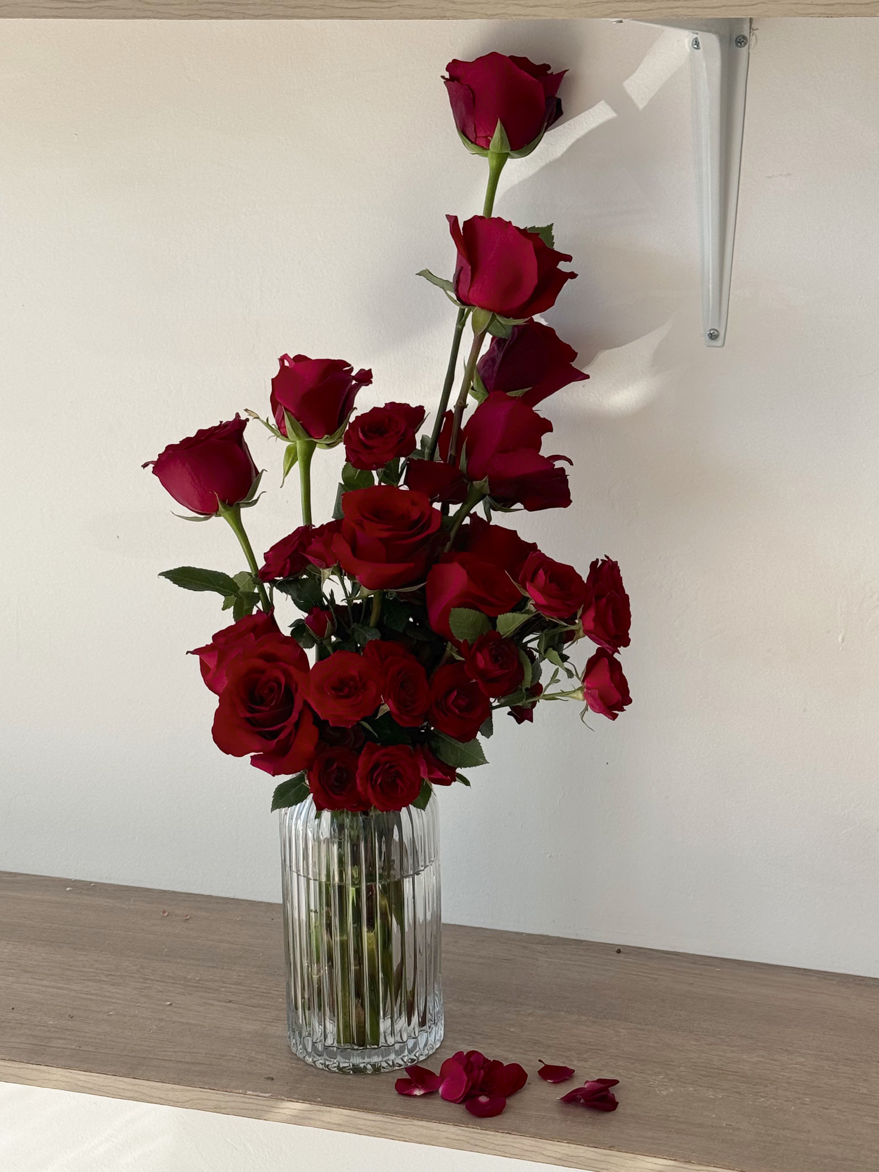 Tall arrangement of red roses in a clear ribbed vase