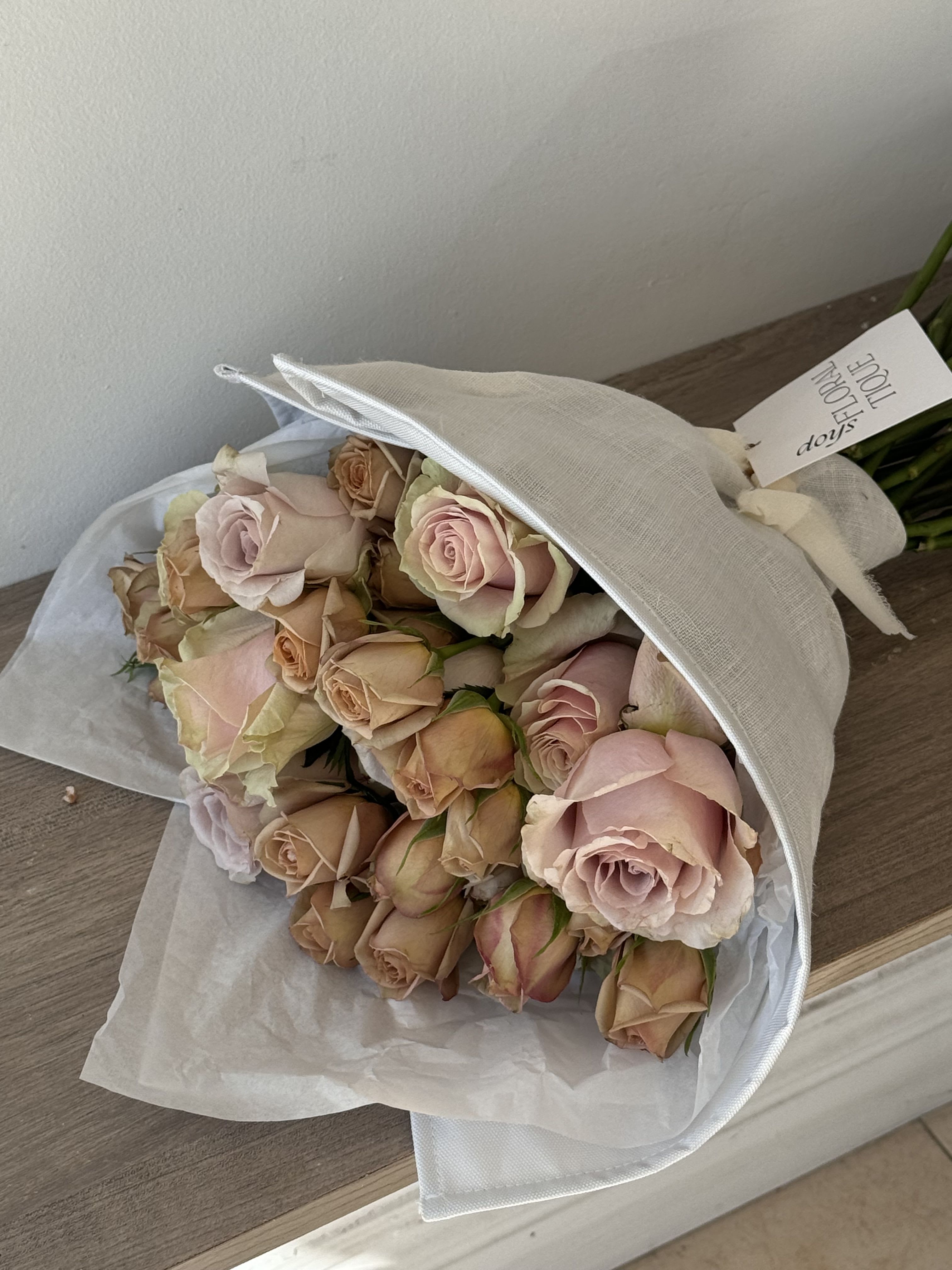 Bouquet of pale pink and peach roses wrapped in white paper