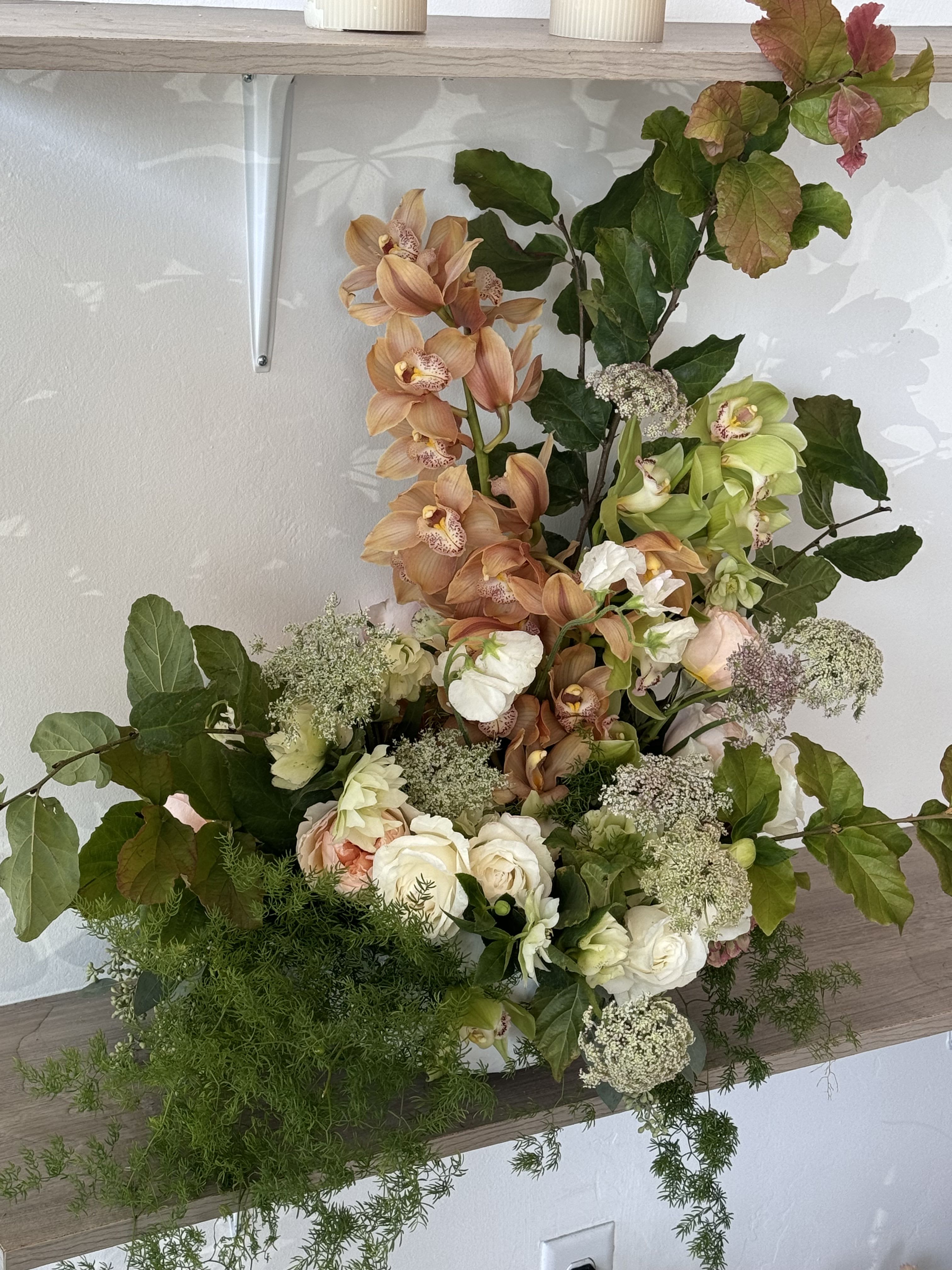 Tall floral arrangement with peach orchids, white roses, and greenery