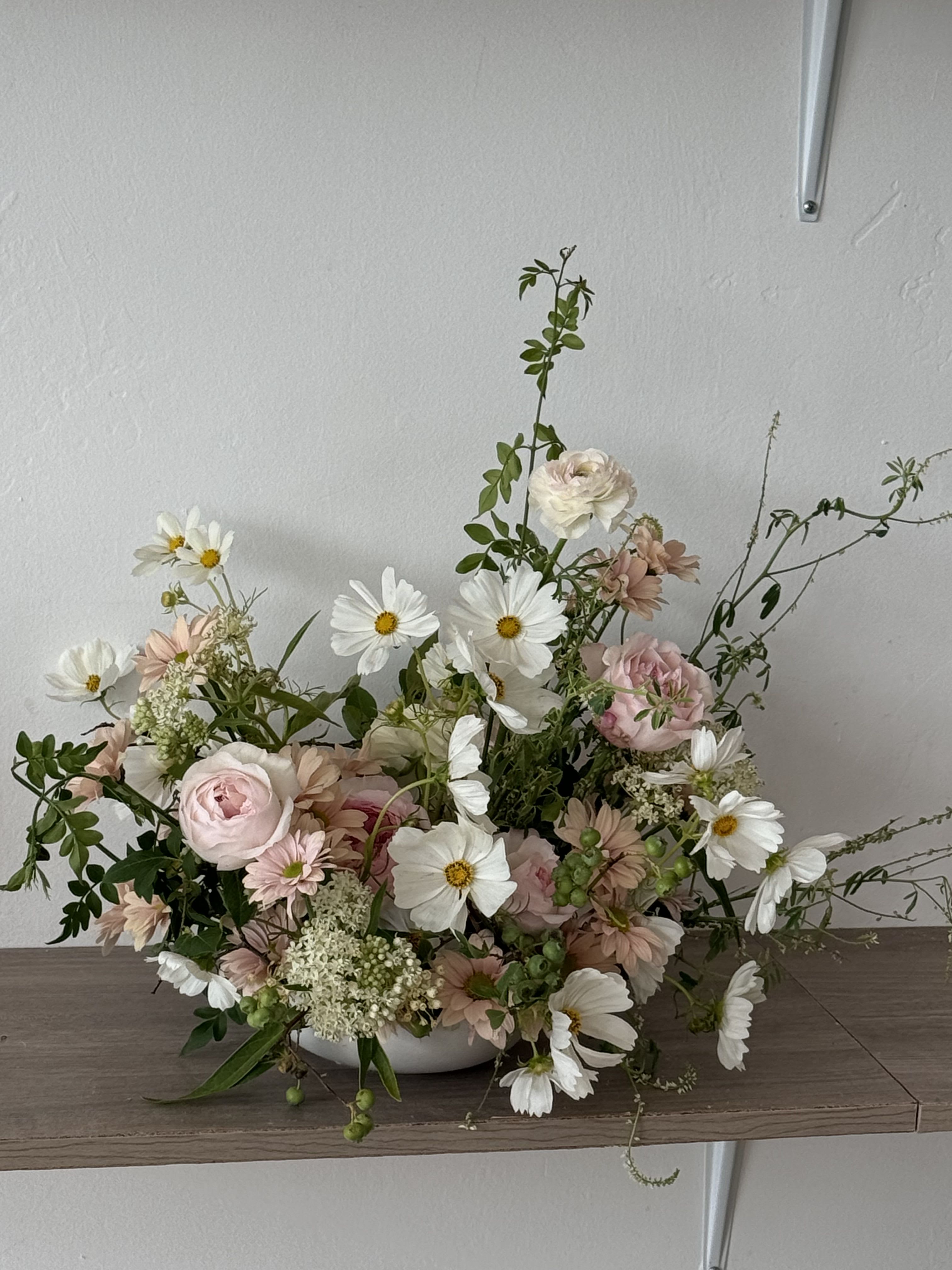Low floral arrangement with pink and white blooms in a white bowl