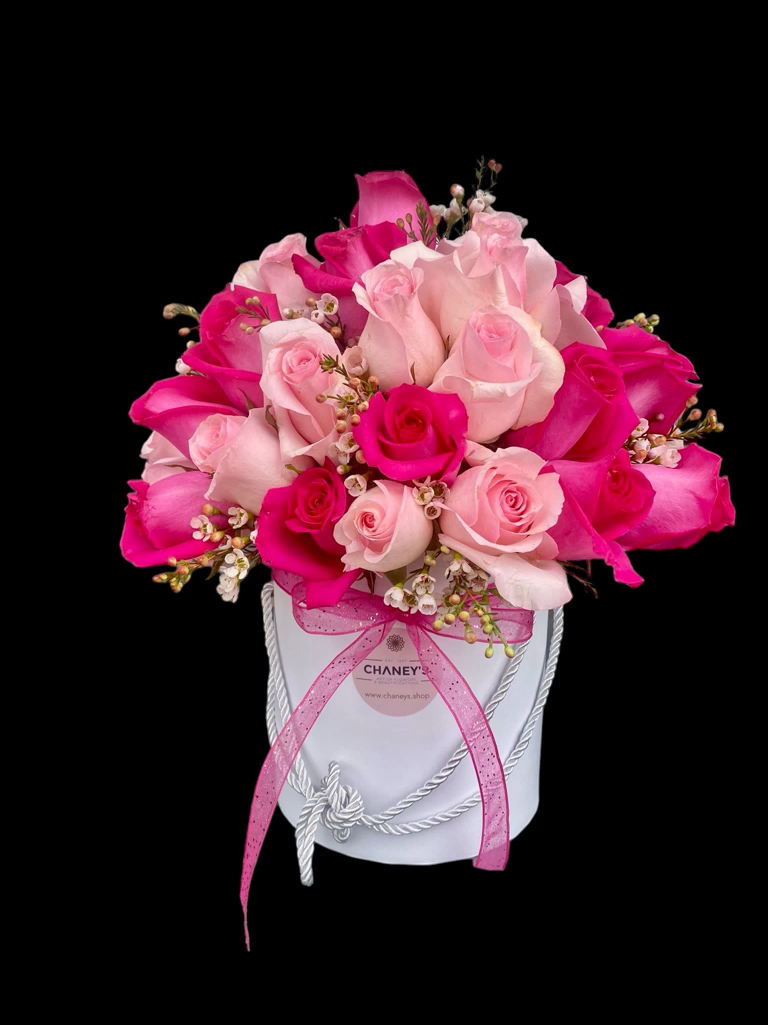 Pink and white roses arranged in a white hat box with a pink ribbon