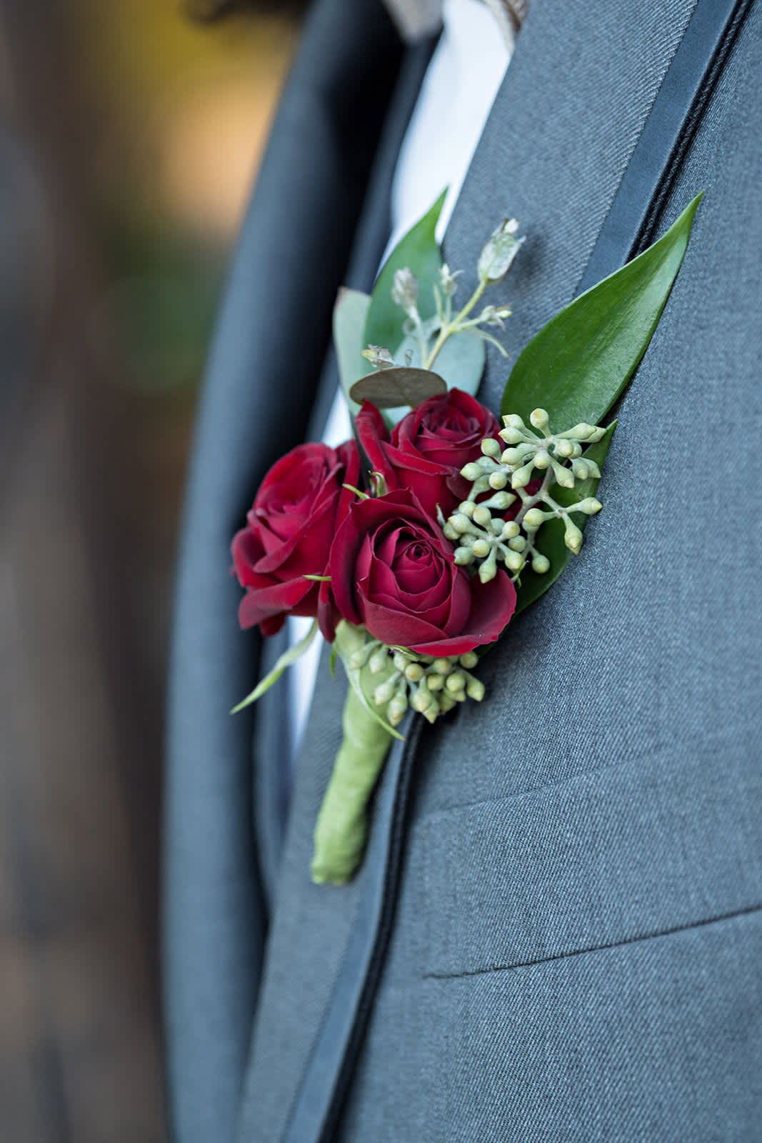 Red rose boutonniere pinned to a gray suit jacket