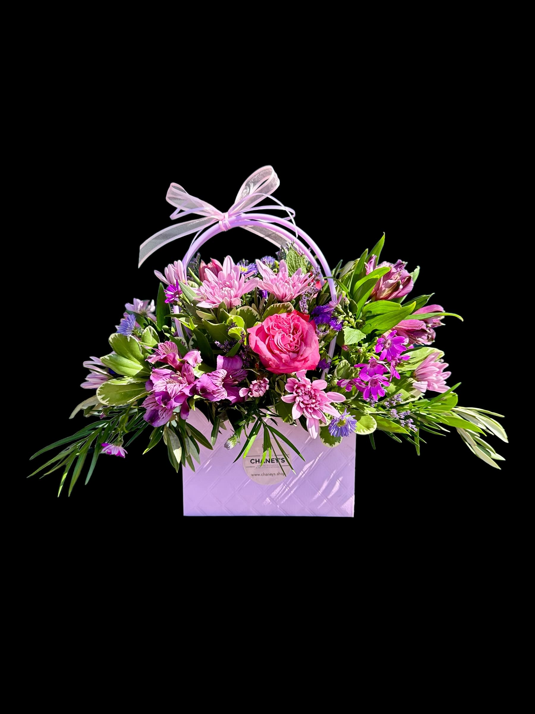 Pink and purple mixed flower arrangement in a lavender gift bag with ribbon handle