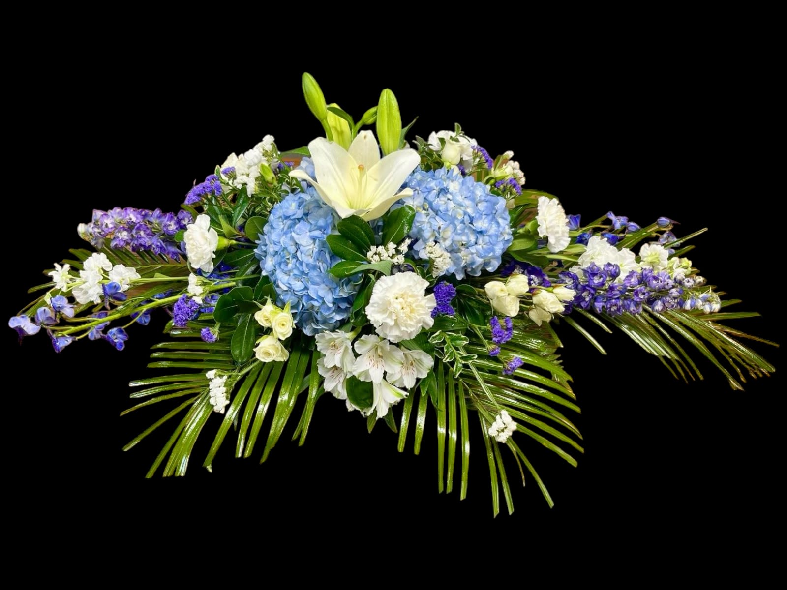 Blue hydrangeas and white lilies in a low floral arrangement