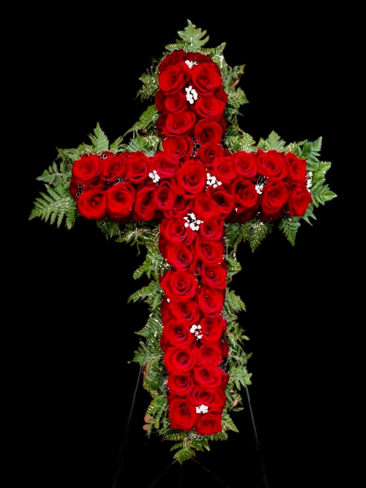 Cross-shaped arrangement of red roses with greenery on a black background