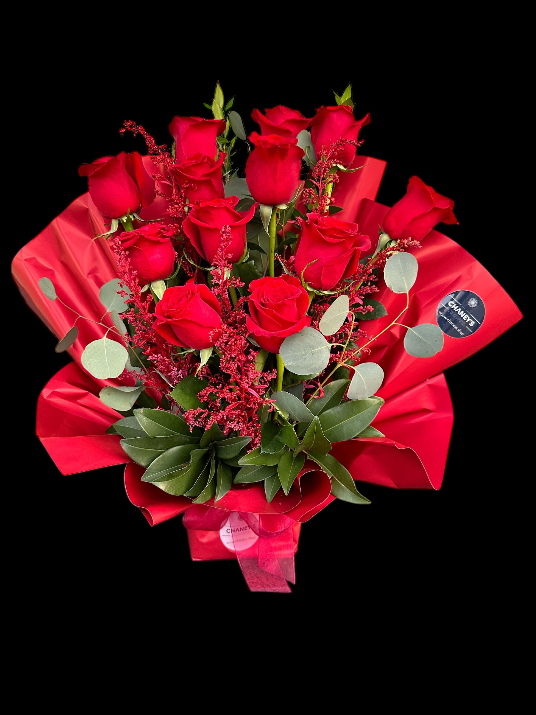 Bouquet of red roses wrapped in red paper with greenery