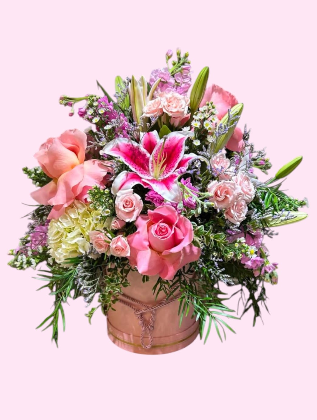 Pink and white floral arrangement in a round box with lilies and roses