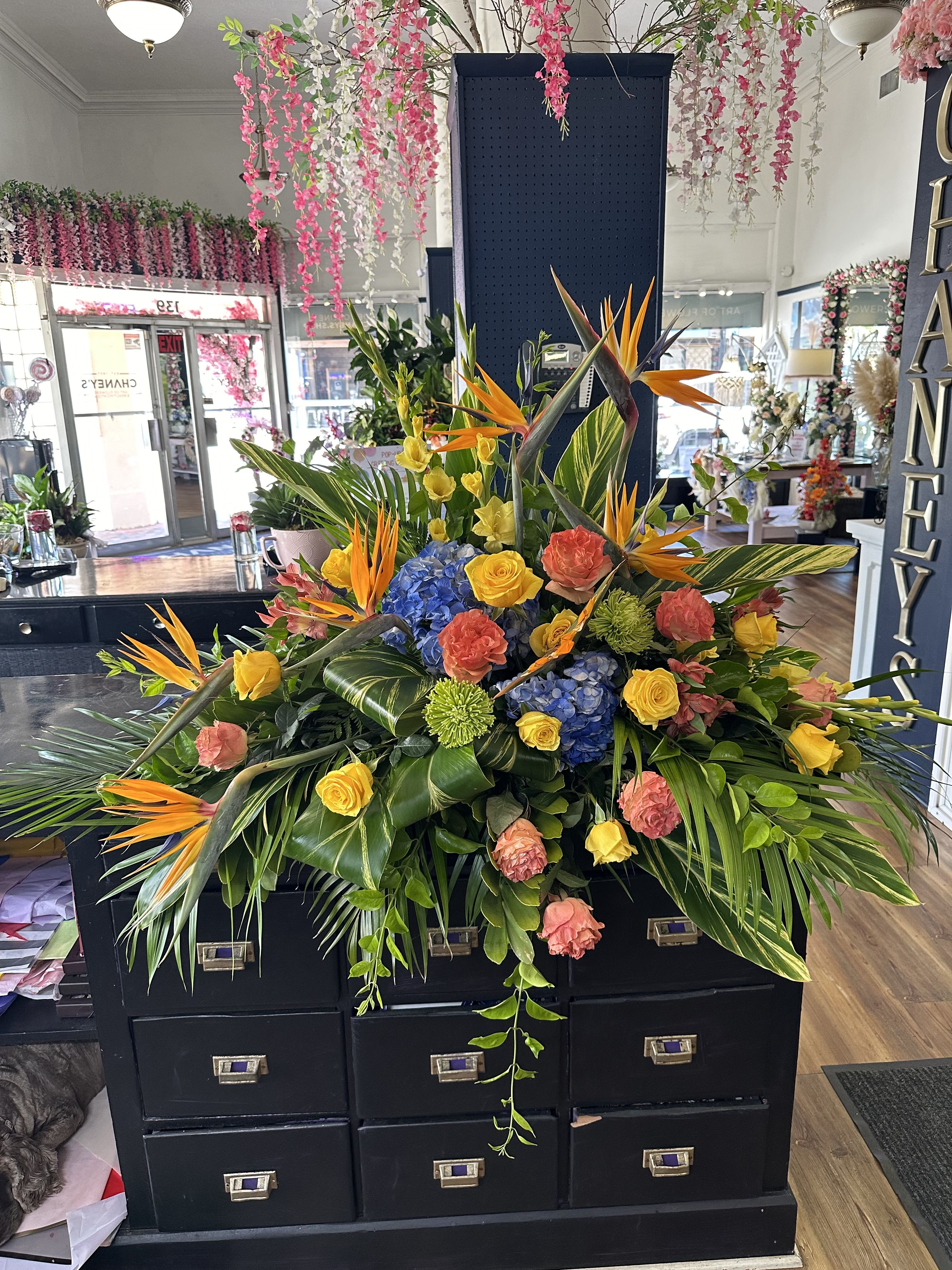 Large tropical floral arrangement with birds of paradise, roses, hydrangeas, and greenery