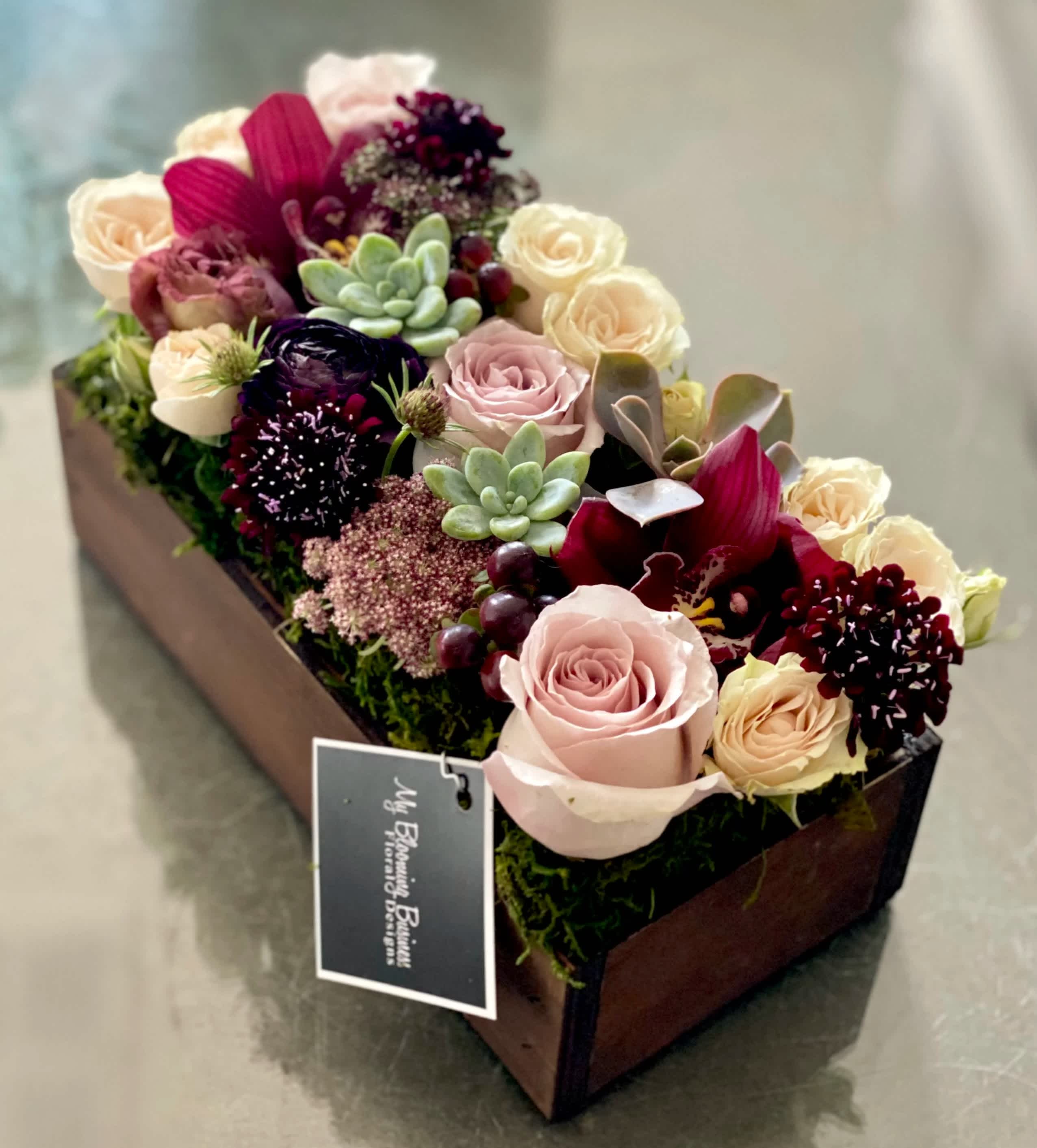 Venice - FB - Ready to turn up the “wow” factor and give someone a truly unique gift? Look no further than our Venice arrangement! This beautiful work of art packs a lot of punch in the form of chrysanthemums, roses, and succulents. Pops of deep burgundy and creams will create an elegant, yet playful, vibe to spread smiles all around. For those “just because” moments, anniversaries, birthdays, or any other occasion, this arrangement is the perfect way to show family and friends how much you care. Standard box 10"X4"X3" Deluxe box 12"X4"X3"