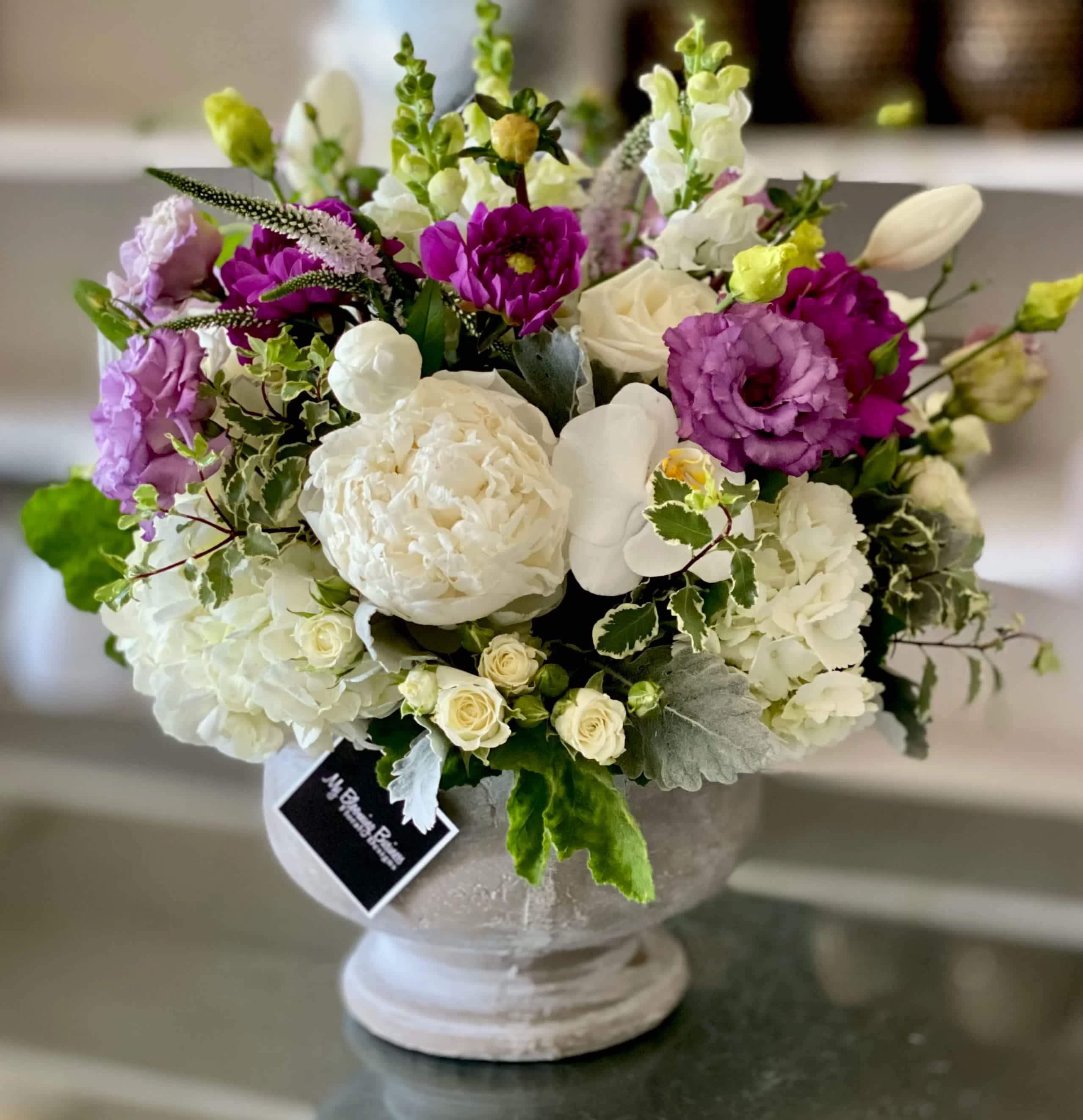 Mia - FB - The Mia Arrangement comes in a stunning masonry pedestal container, adding an extra touch of elegance to an already exquisite masterpiece. It's like housing a fairytale in a chic, contemporary setting.   But enough about the details, let's talk about the effect Mia will have on your special someone. When they receive this enchanting bouquet, their heart will melt like butter on a hot summer's day. They'll be captivated by its delicate charm, and won't be able to resist getting lost in its petals. 