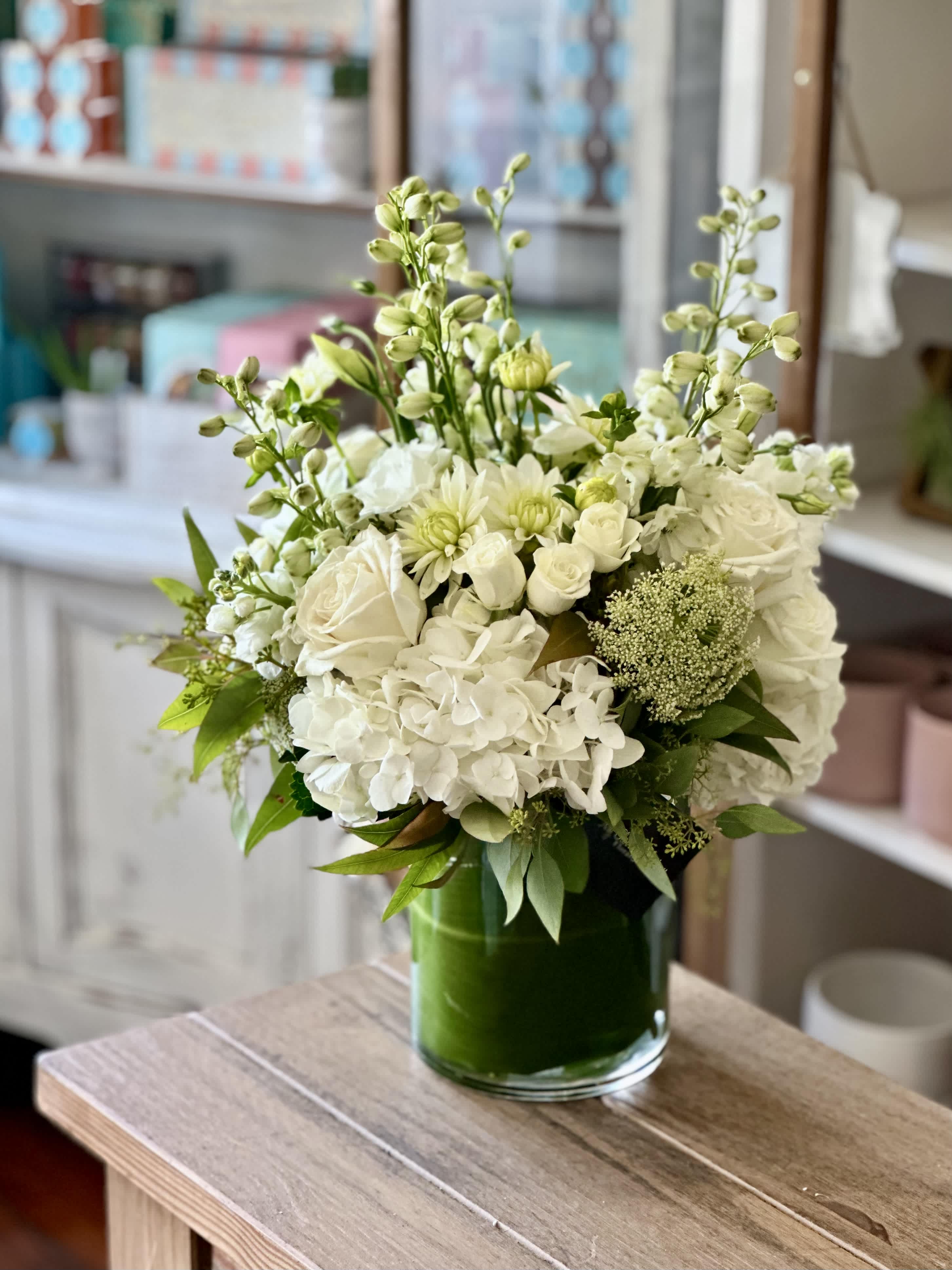 Palos Verdes - FB - The Palos Verdes Arrangement is a mix of white and green florals such as roses, hydrangeas, and greenery in a t leaf lined vase. 