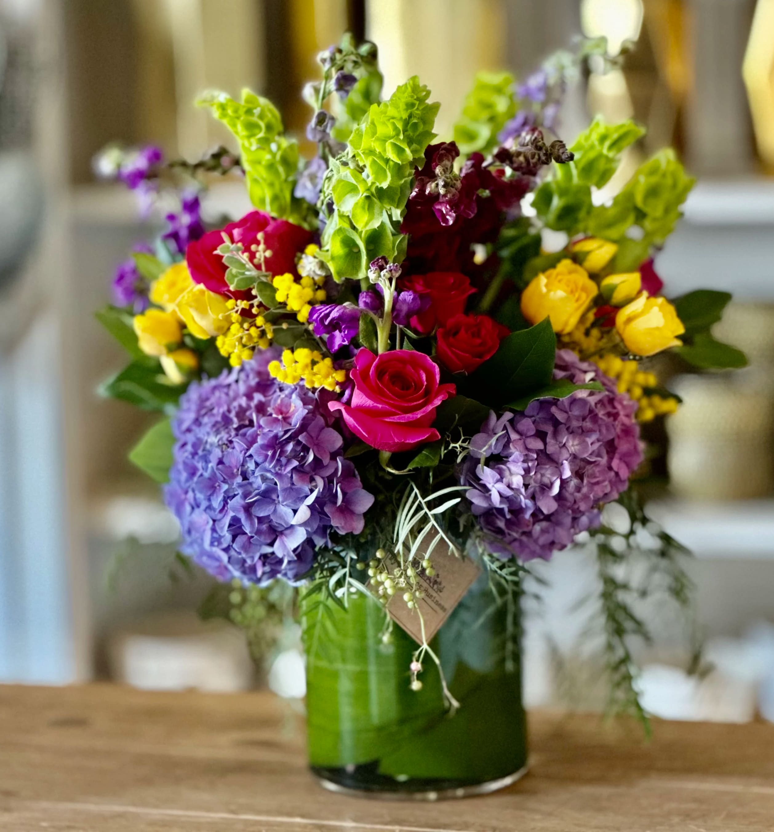 Colorful bouquet of roses, hydrangeas, and snapdragons in a glass vase
