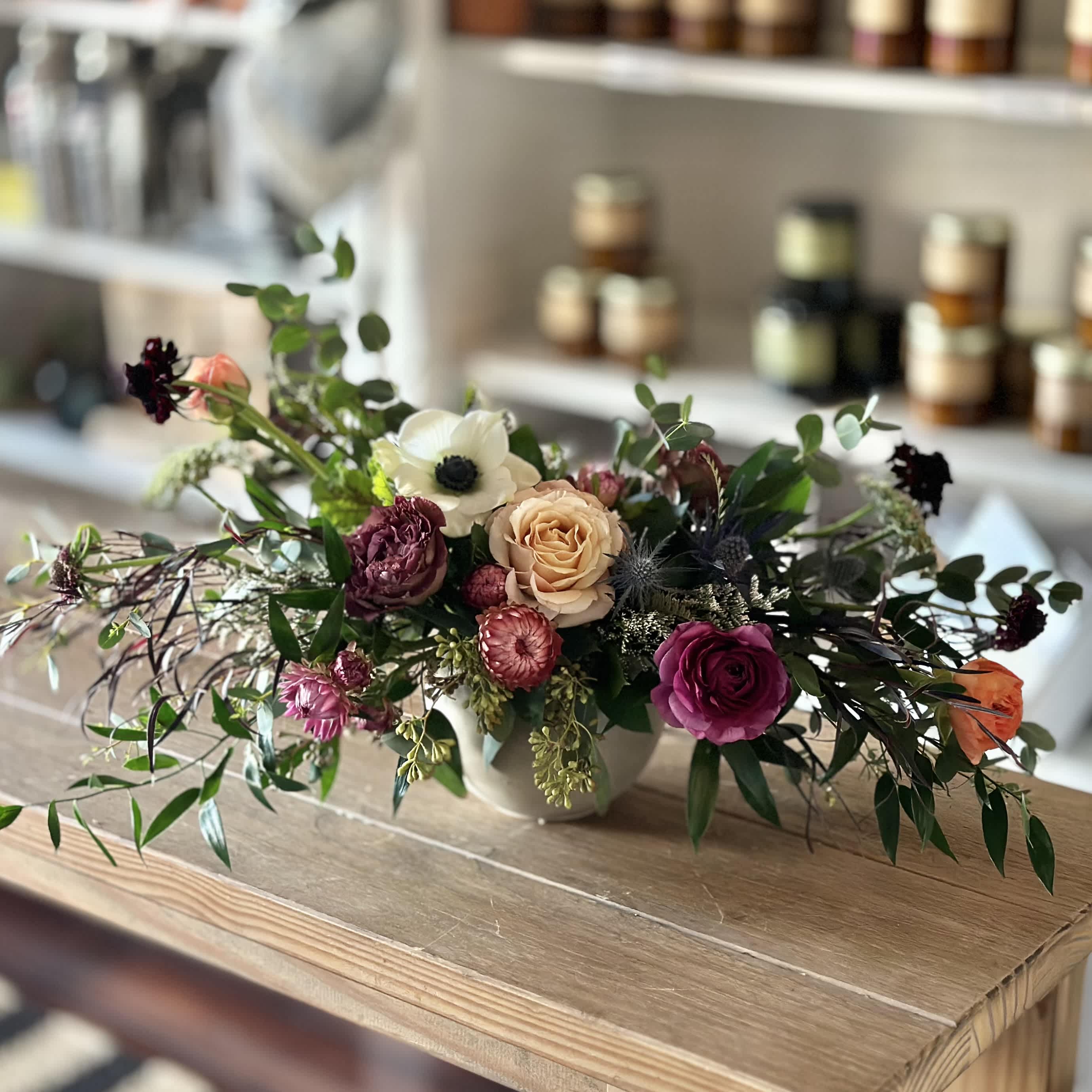 Low floral arrangement with roses and anemone in a white vase