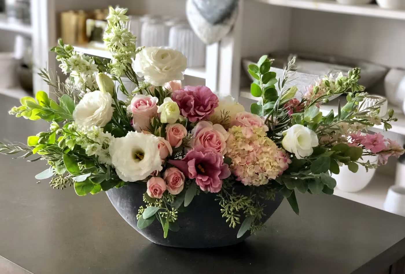 Mixed floral arrangement in a dark bowl vase with pink, white, and purple blooms
