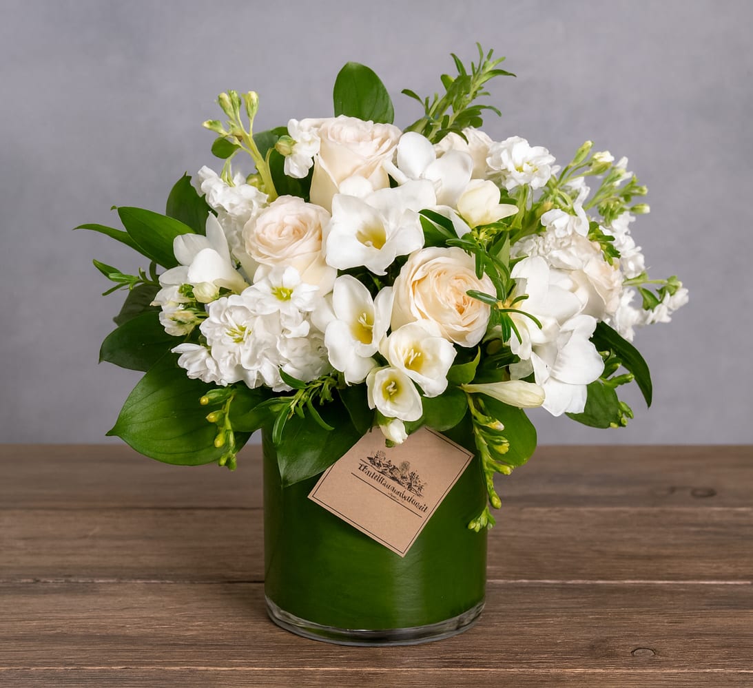 White and cream floral arrangement in a green glass vase