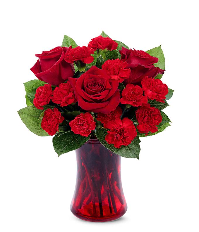Red roses and carnations arranged in a red glass vase