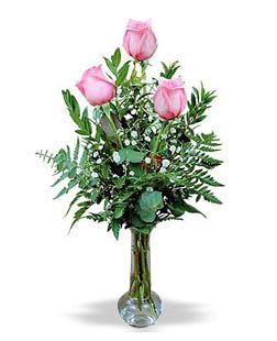 Pink roses in a clear glass vase with greenery