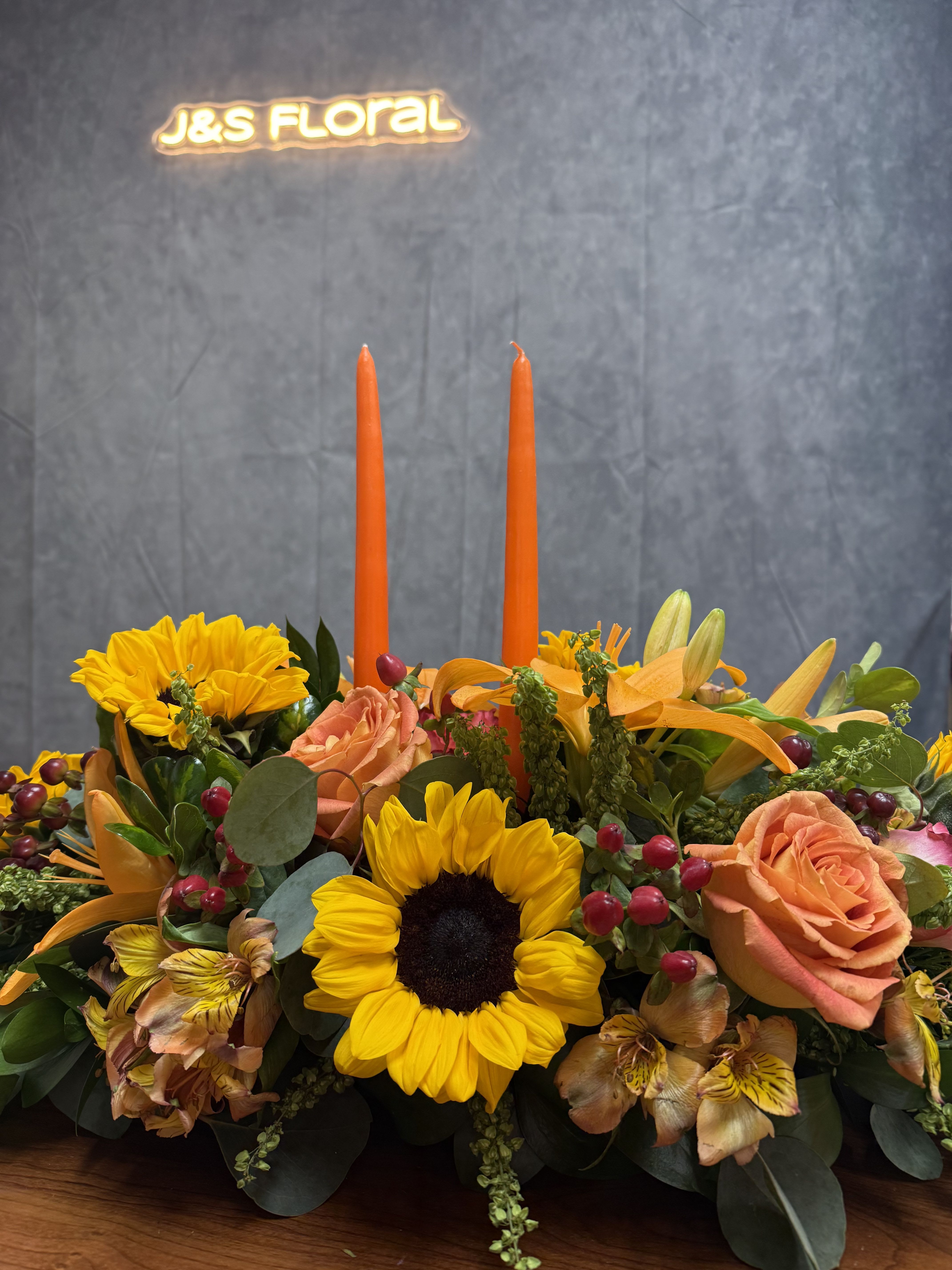 Fall Fiesta  - Embrace the beauty of autumn with our exquisite fall Fiesta arrangements! Handcrafted with vibrant hues of fall colors, our arrangements capture the essence of the season. The flower arrangement is 2ft long in the picture and it include two candles. Perfect for adding a touch of fall to any space or event.