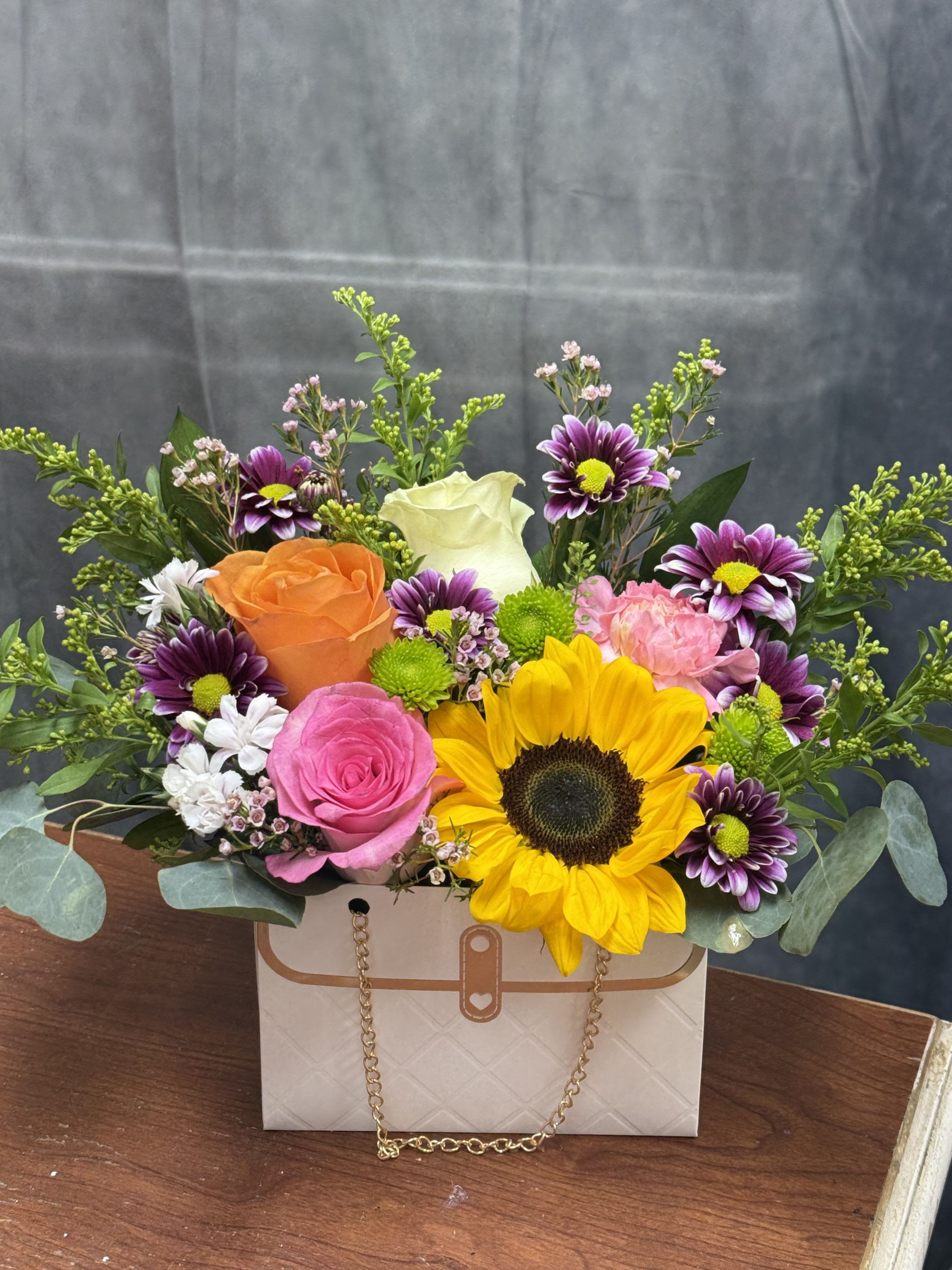 Chic Garden Purse  - Sunflower-centered mixed  with pink, orange, purple and cream blooms in a Chic Garden Purse flower arrangement cheerful and perfect for birthdays, thank you , or just because.