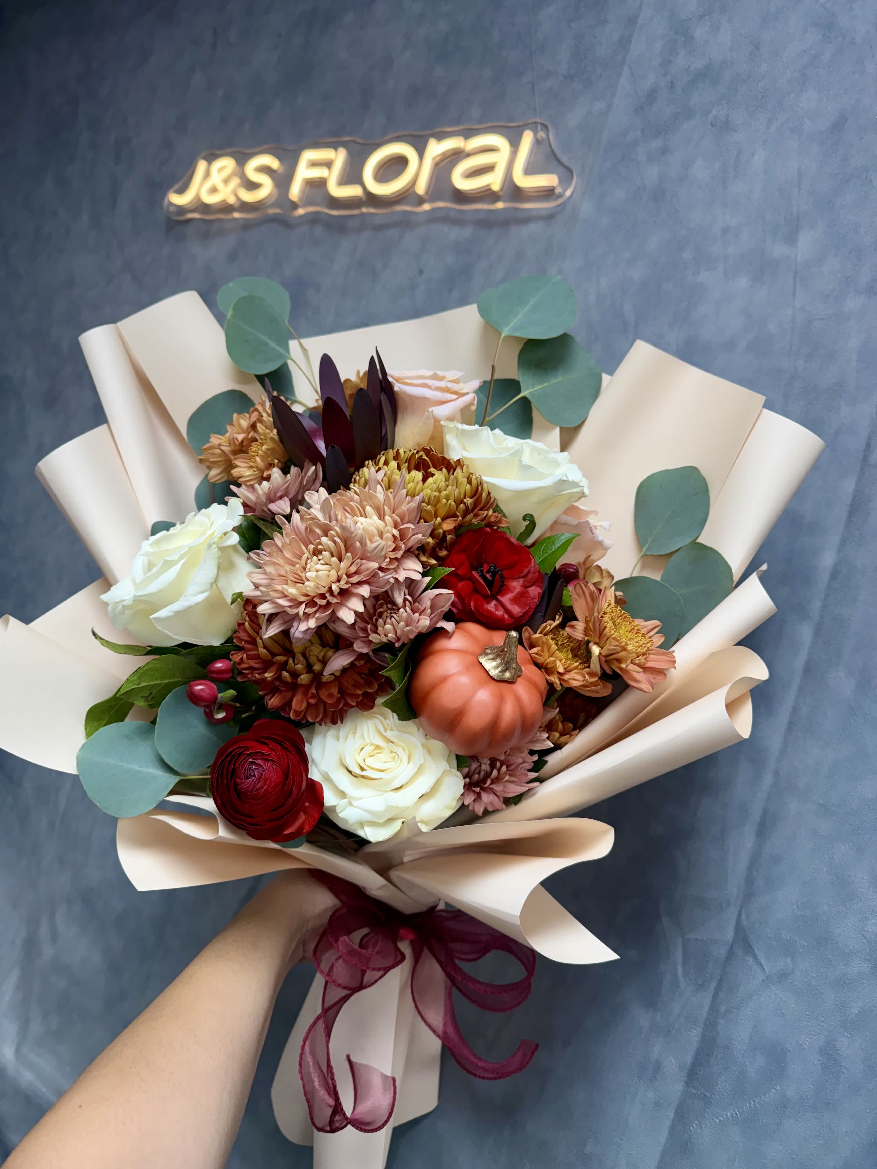 Hand-tied bouquet of roses, chrysanthemums, and a small pumpkin wrap