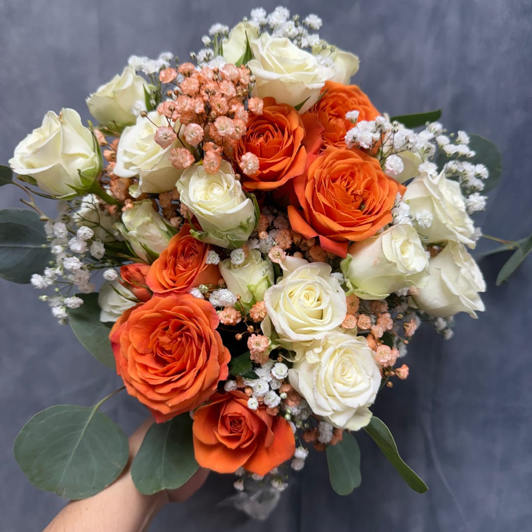 Bouquet of orange and white roses with small filler flowers