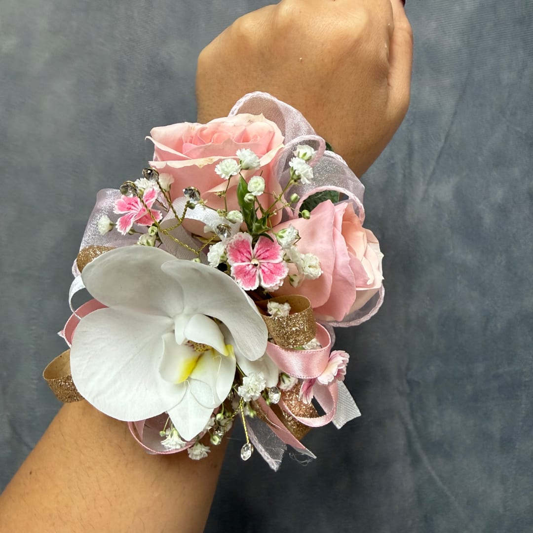 Pink rose corsage with a white orchid and ribbon on a wrist