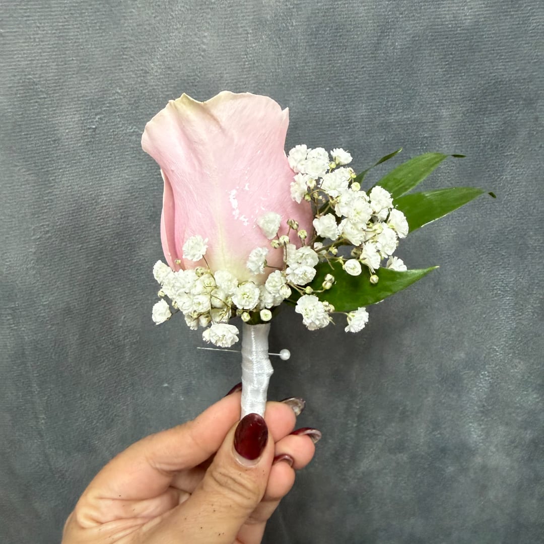 Pink rose boutonniere with white baby's breath and green leaves