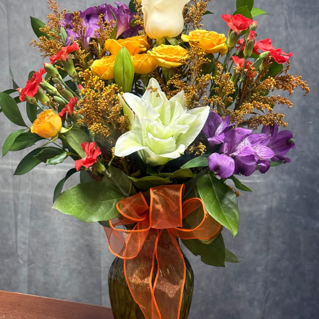 Colorful bouquet in a dark glass vase with an orange ribbon