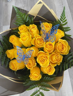Bouquet of yellow roses with fern foliage and butterfly picks