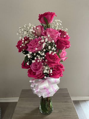 Pink rose bouquet in a glass vase with baby's breath and a ribbon bow