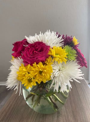 Colorful bouquet of roses and daisies in a round glass vase