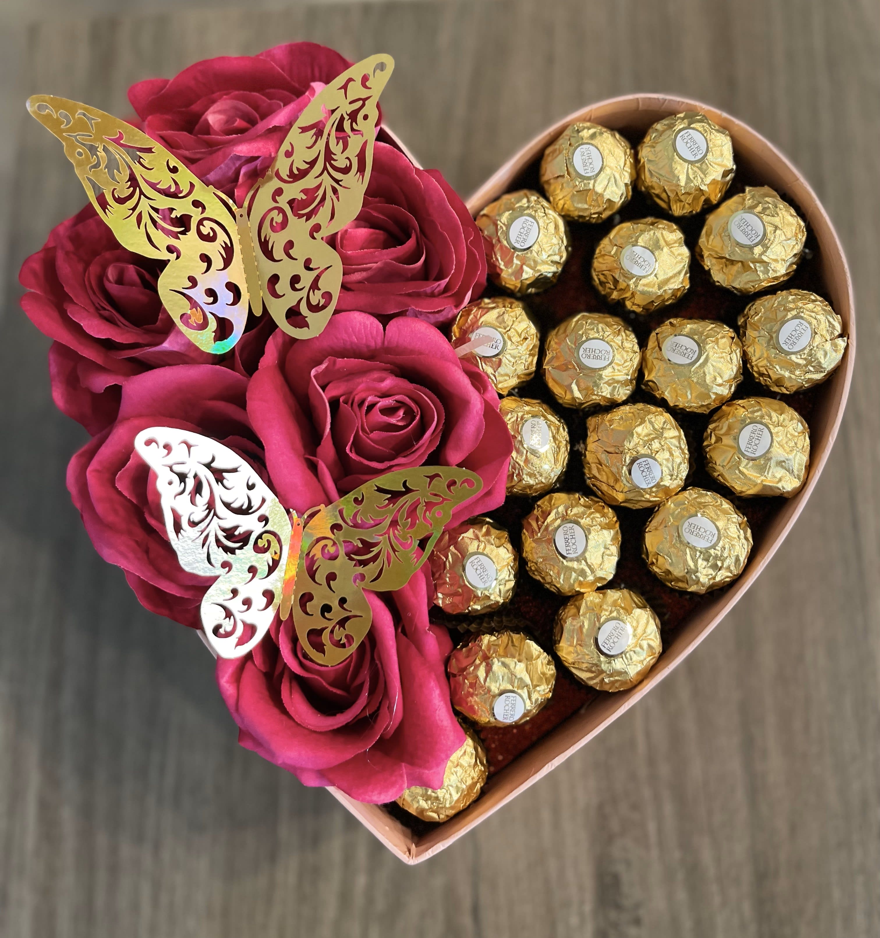 Heart-shaped box with pink roses and gold-wrapped chocolates