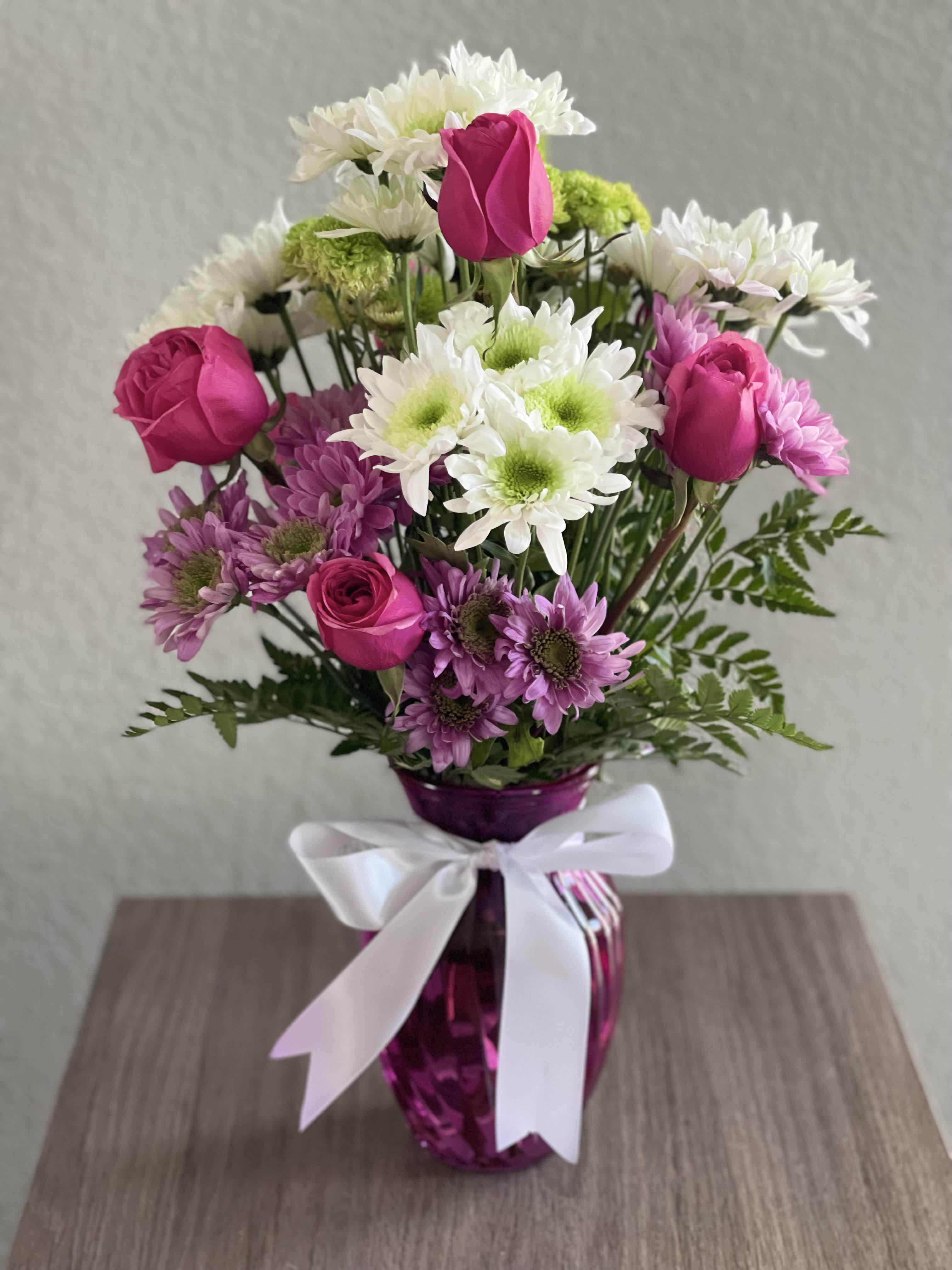 Pink roses and white daisies in a purple vase with a white ribbon