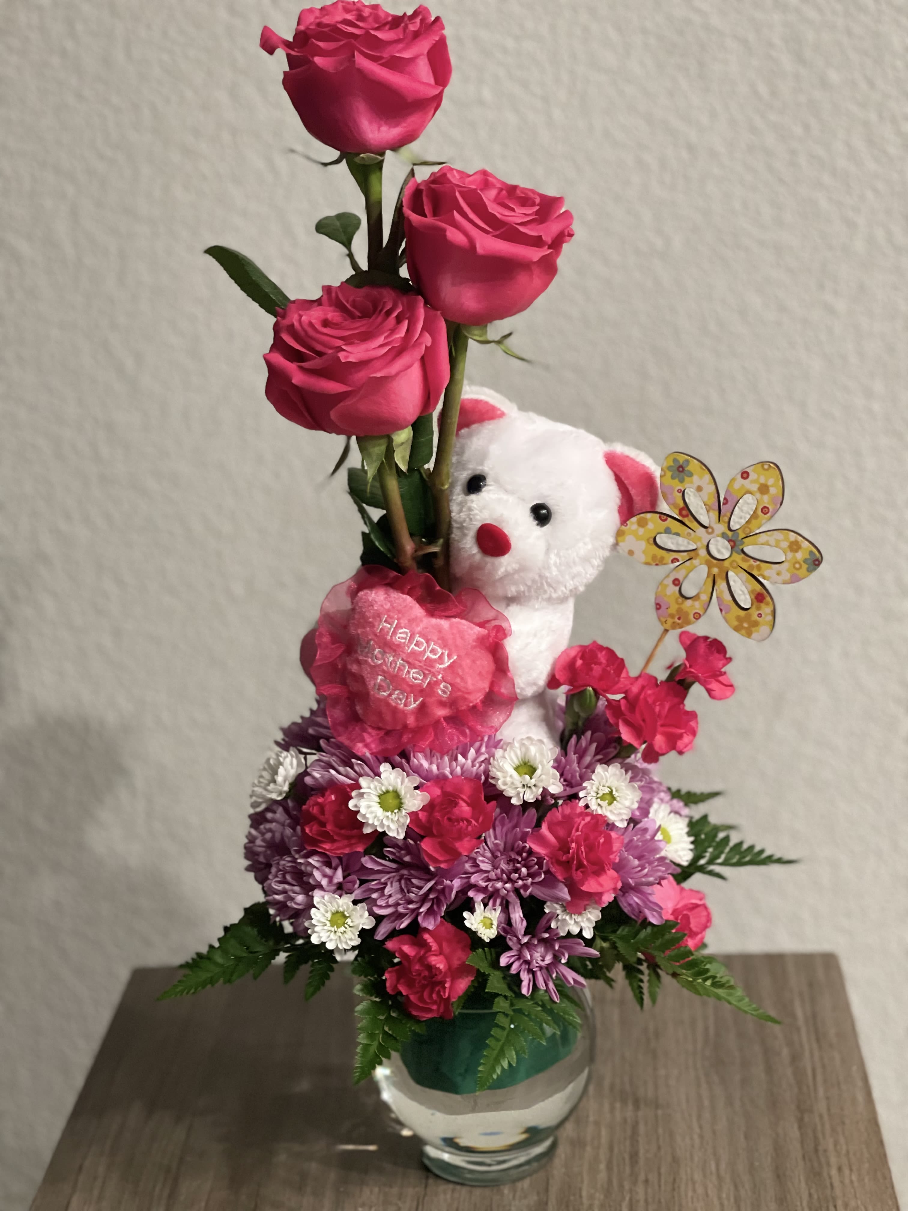Pink rose arrangement with a teddy bear and flowers in a glass vase