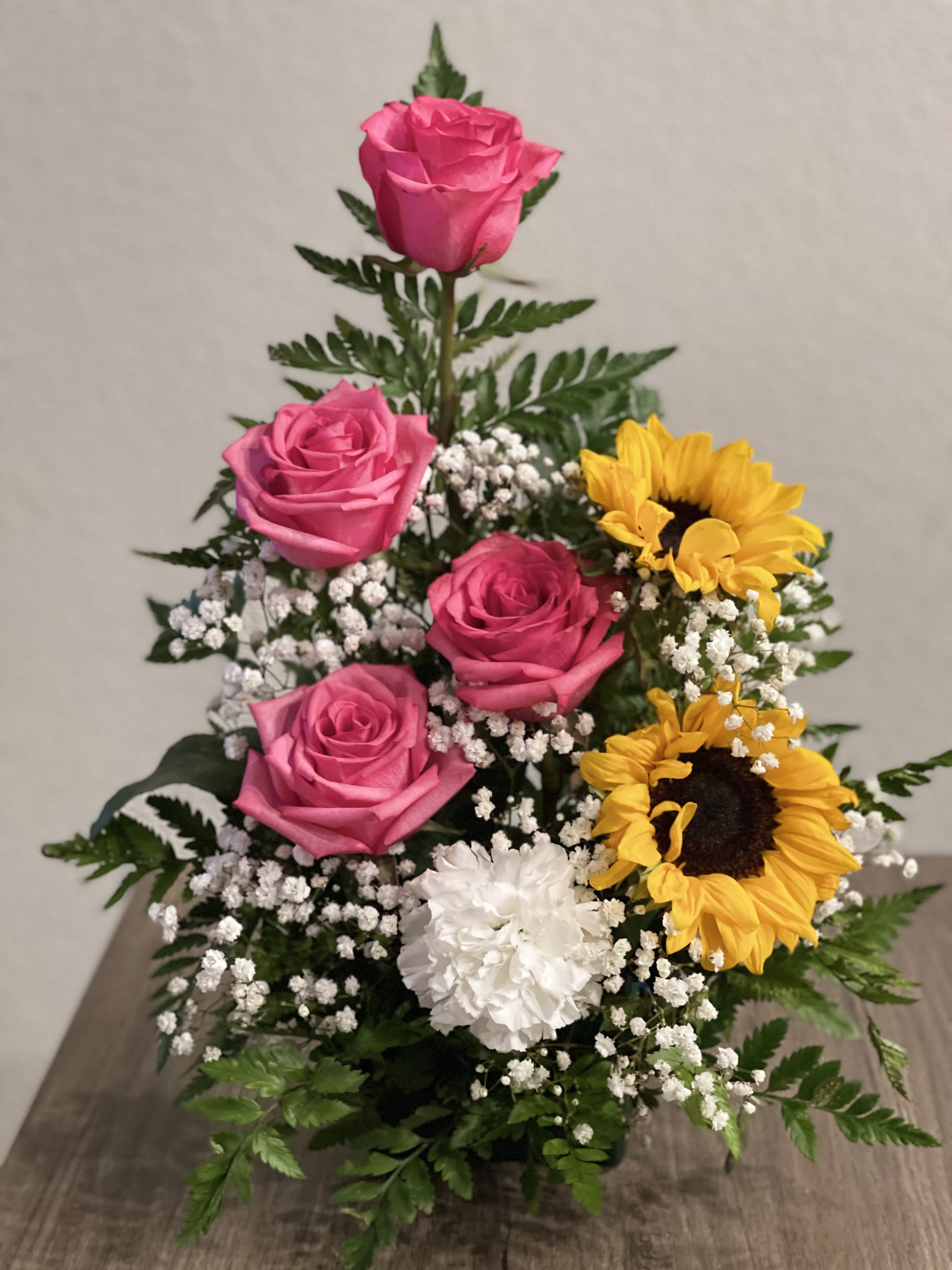 Pink roses and sunflowers arranged with white filler flowers