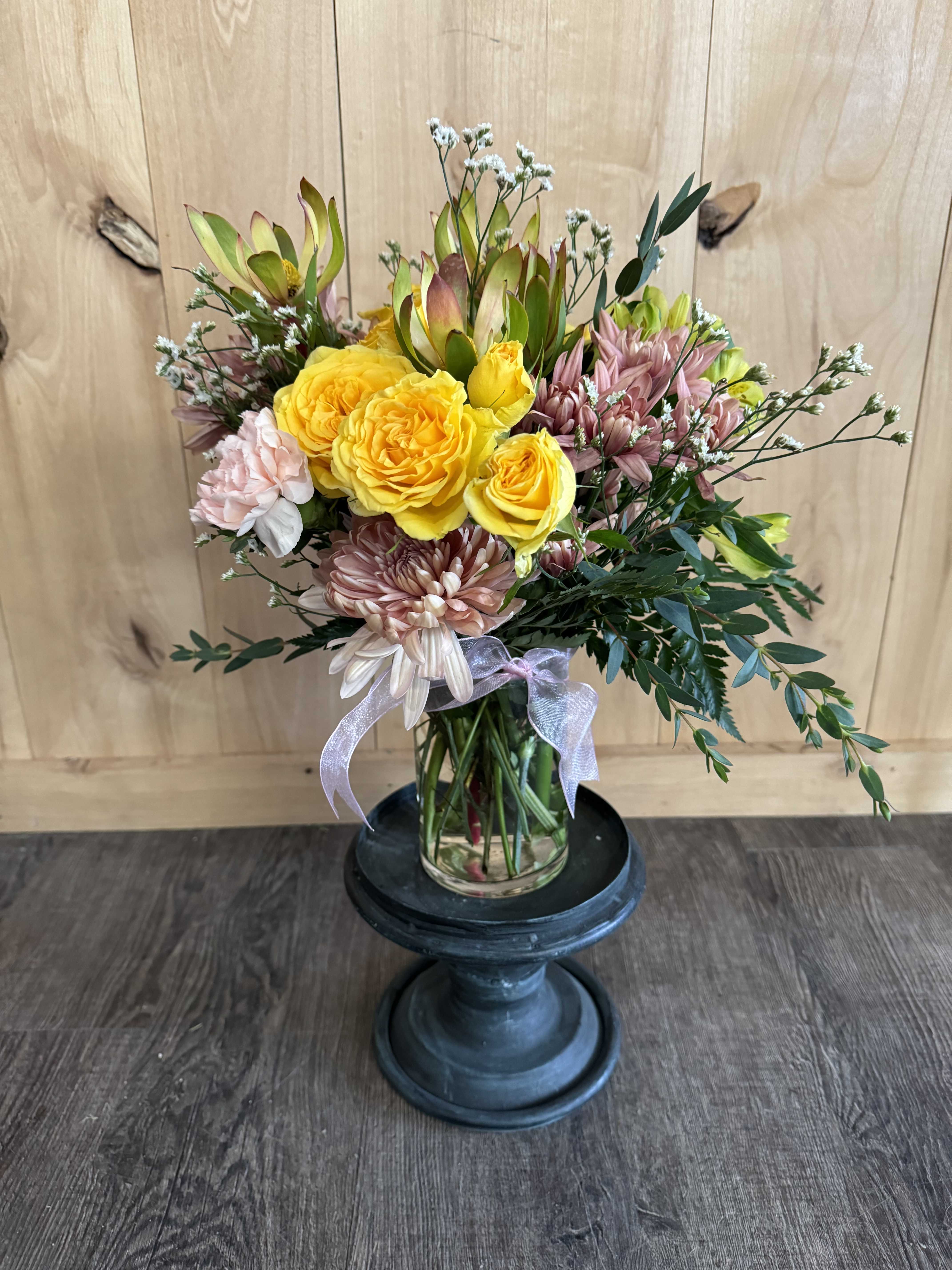 Bouquet of yellow roses and pink chrysanthemums in a glass vase