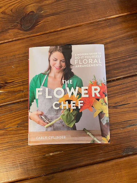 A floral arrangement guide book on a wooden table