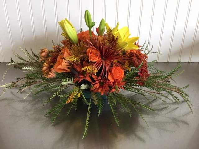 Orange and yellow floral arrangement in a low container