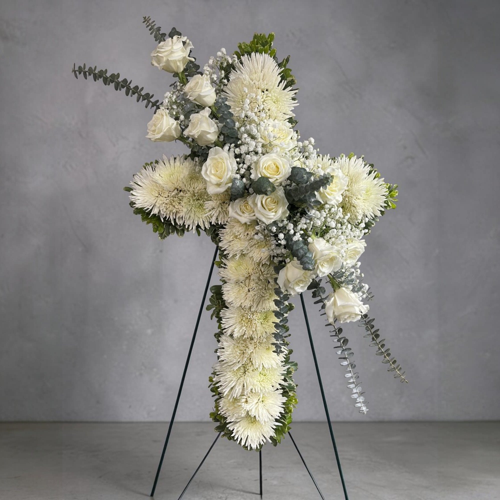Faithful Servant - Honor a cherished life with this graceful white cross standing spray. Designed with an elegant assortment of fresh white blooms, it symbolizes peace, purity, and everlasting love, offering a heartfelt tribute and a beautiful expression of remembrance.
