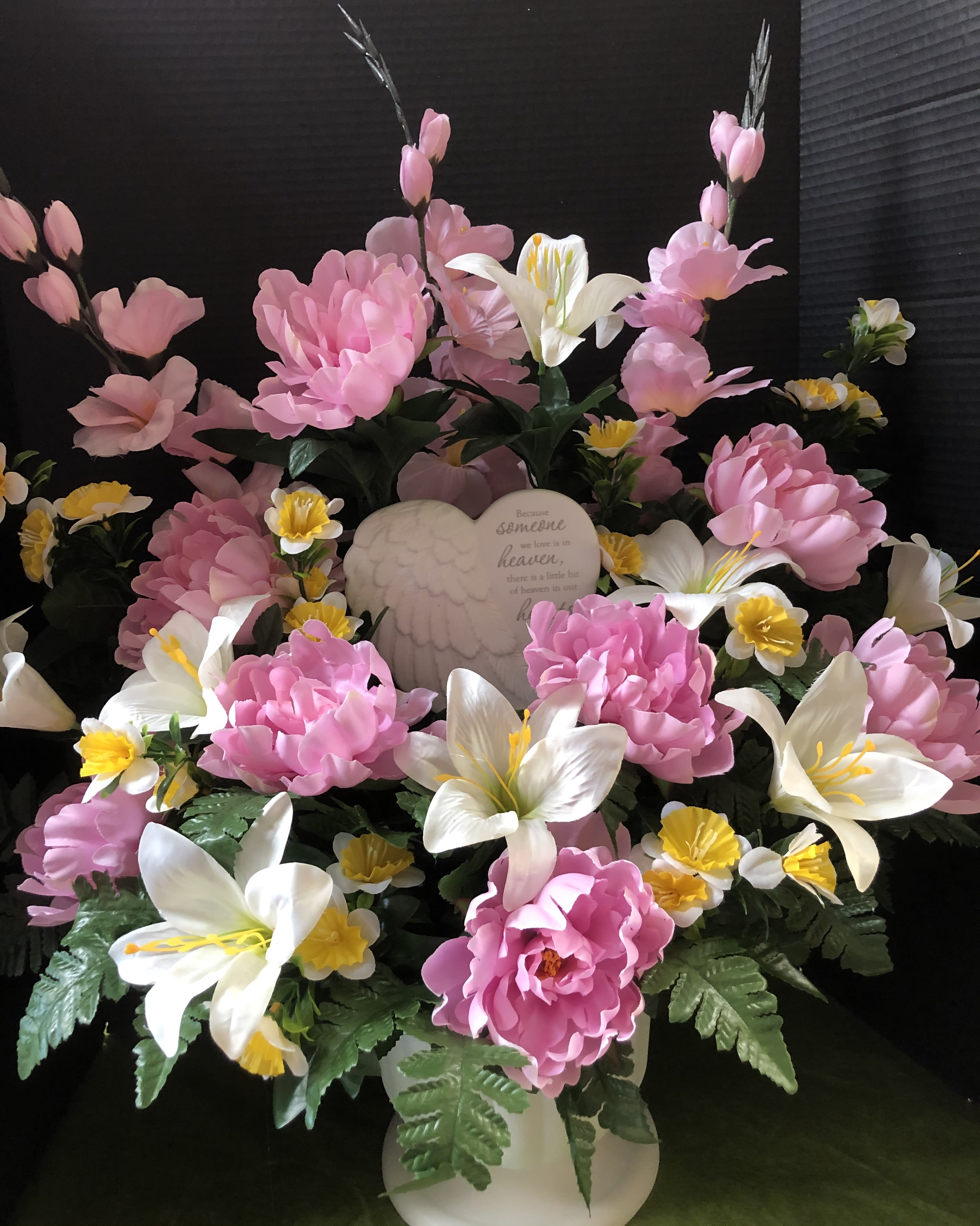 Pink and white floral arrangement with an angel plaque in a white vase