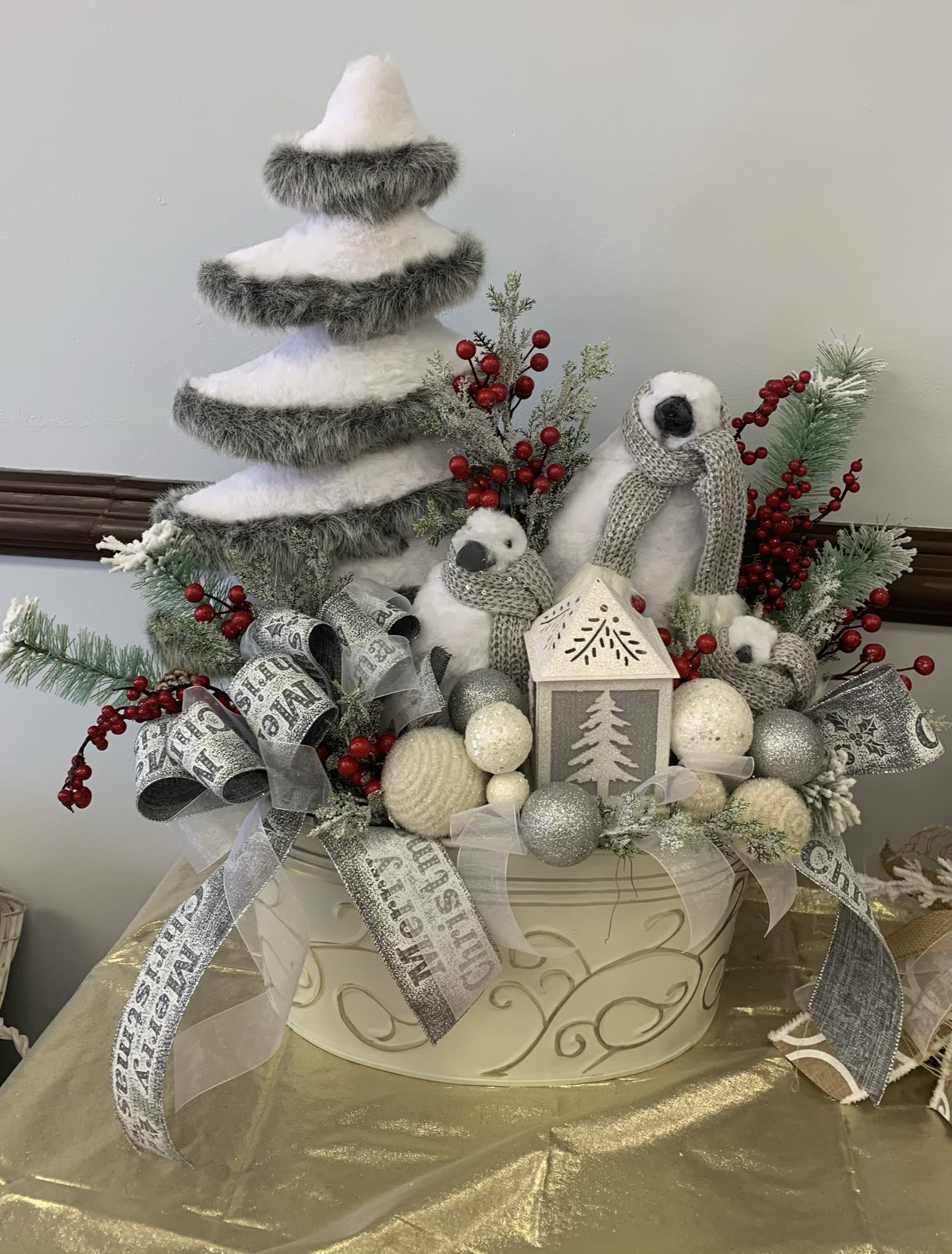 Winter holiday centerpiece with a faux tree, penguins, and silver ribbons