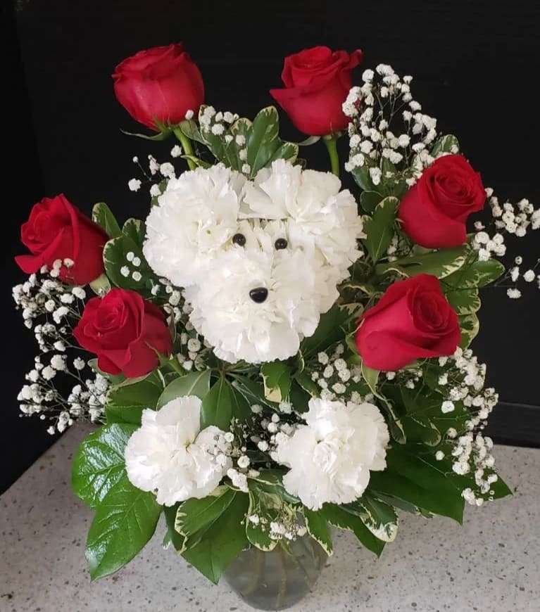Red roses and white carnations arranged in a vase with baby's breath