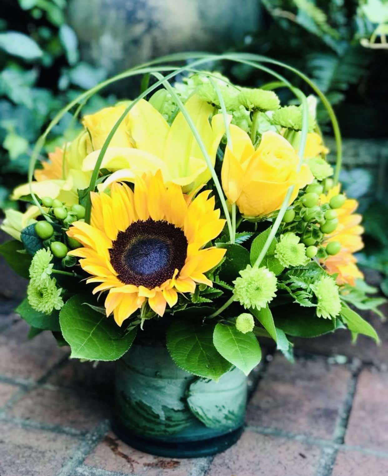 Yellow sunflower and rose arrangement in a green vase