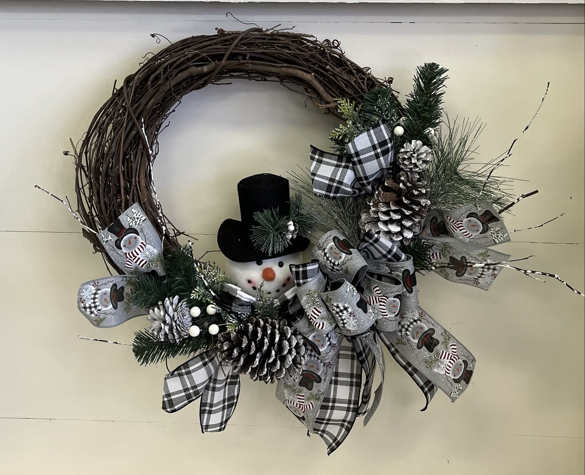 Christmas wreath with a snowman, pinecones, and plaid ribbon