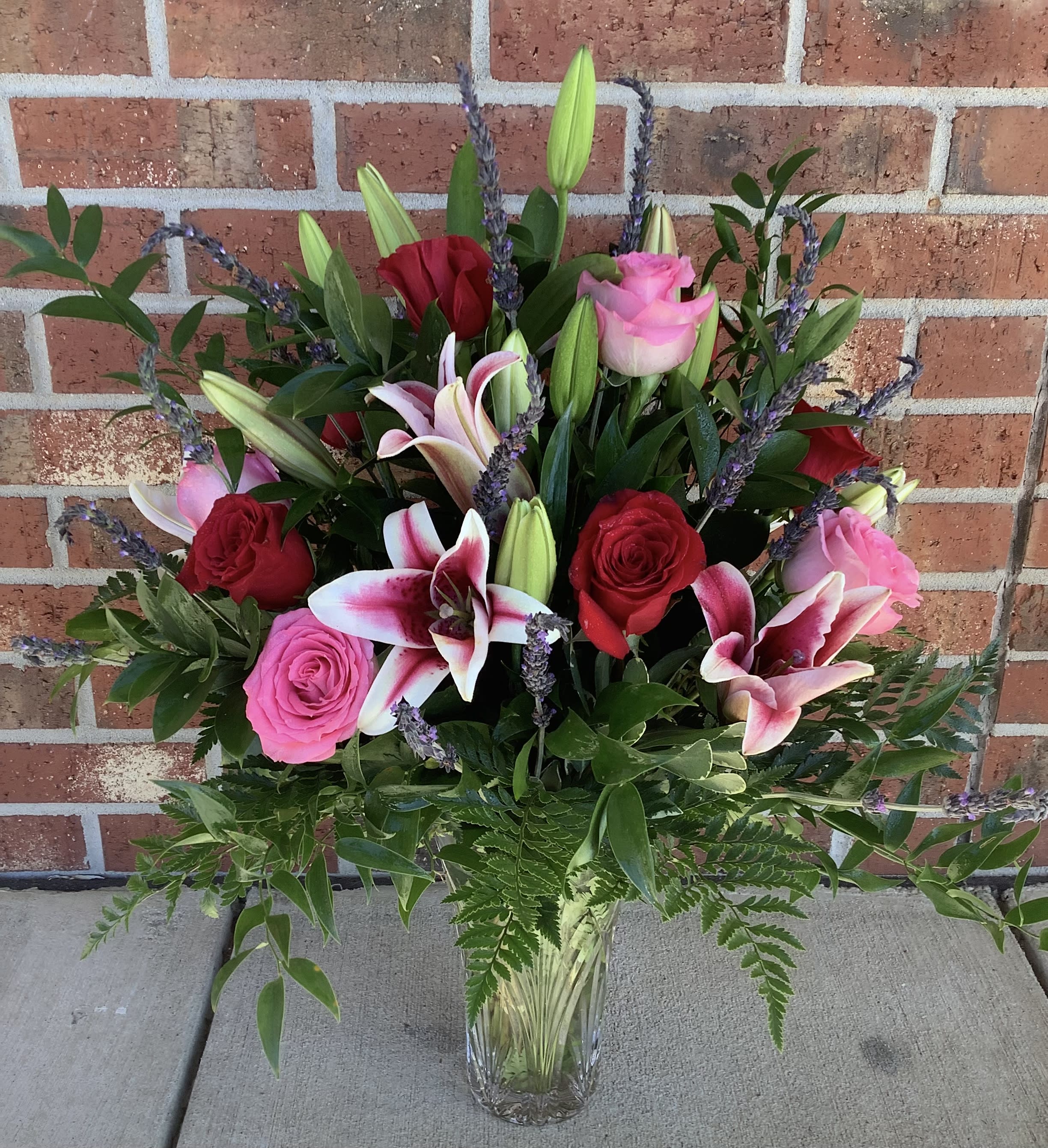 Mixed bouquet of pink and red roses with lilies in a glass vase
