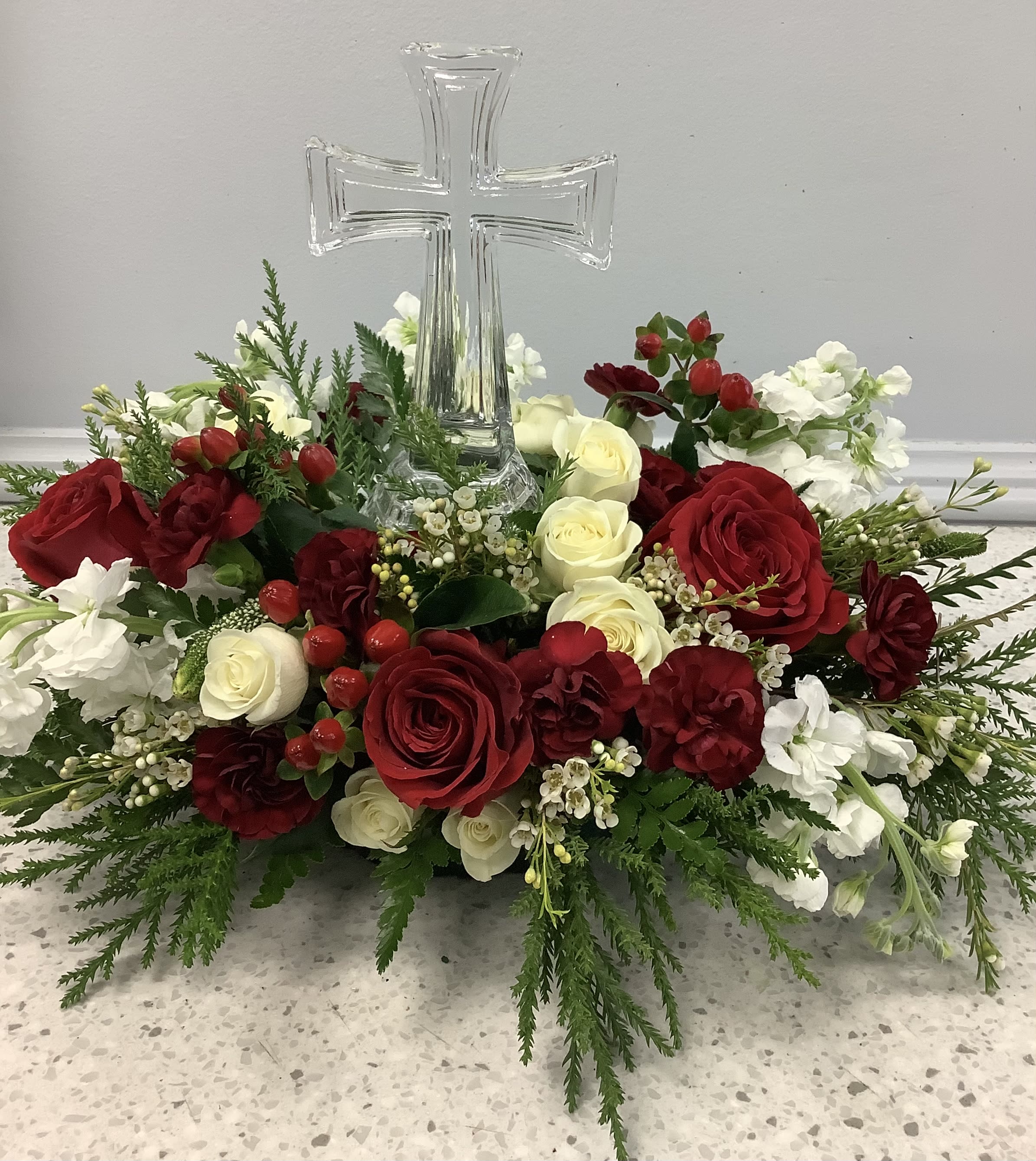 Red and white rose arrangement with a clear glass cross