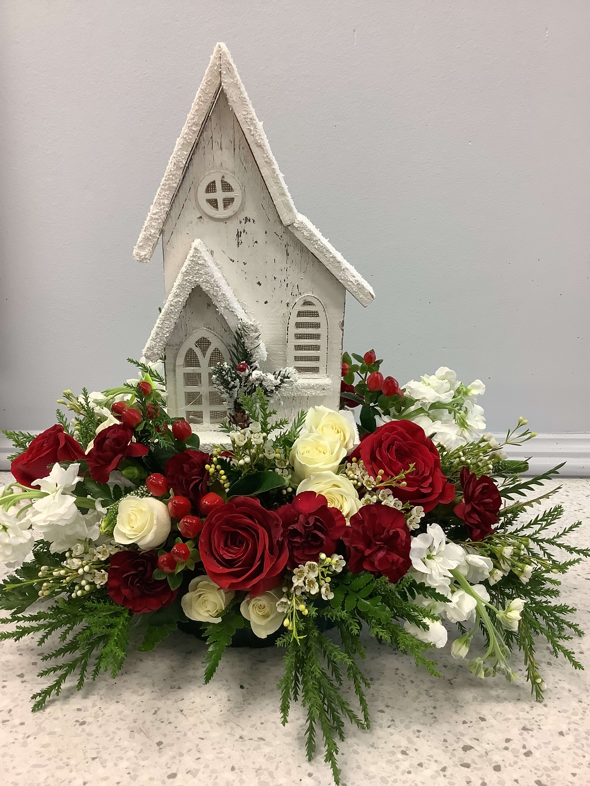 Red and white floral arrangement around a small white church decoration